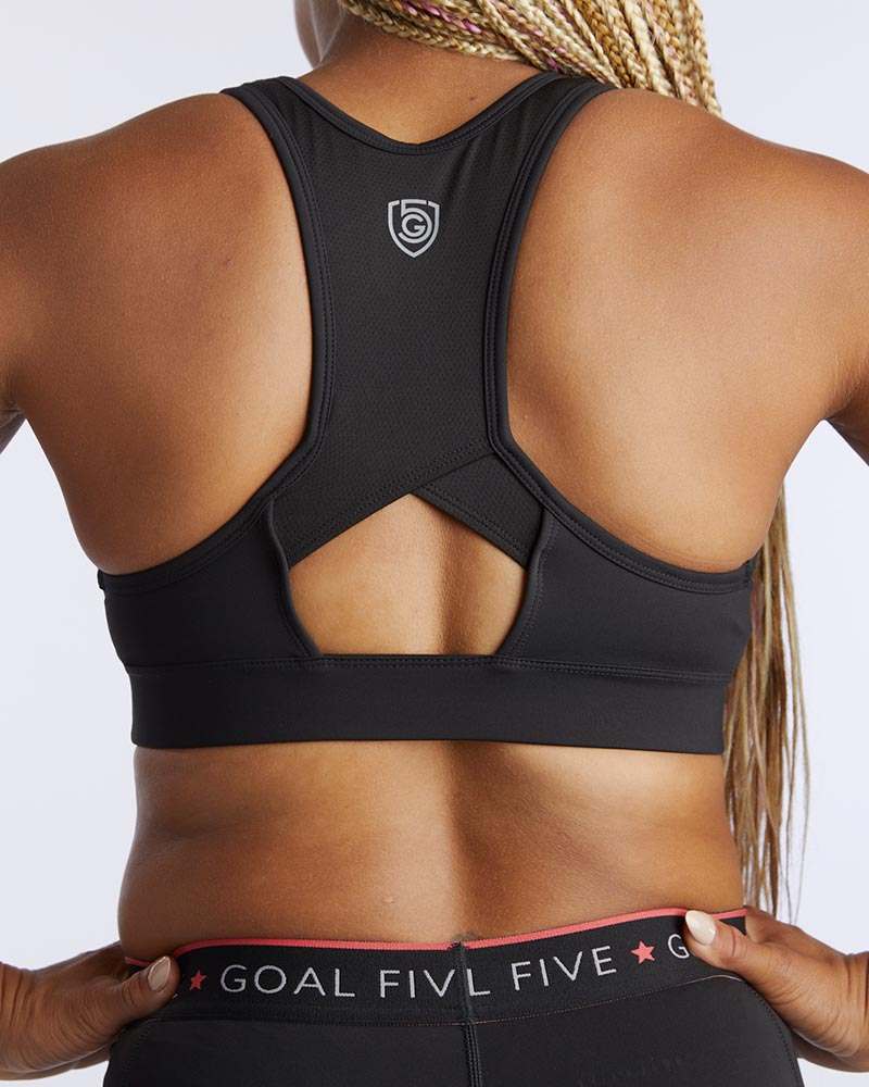 99'er Padded Sports Bra in black stretch fabric, featuring a racerback with a geometric open cutout and small crest