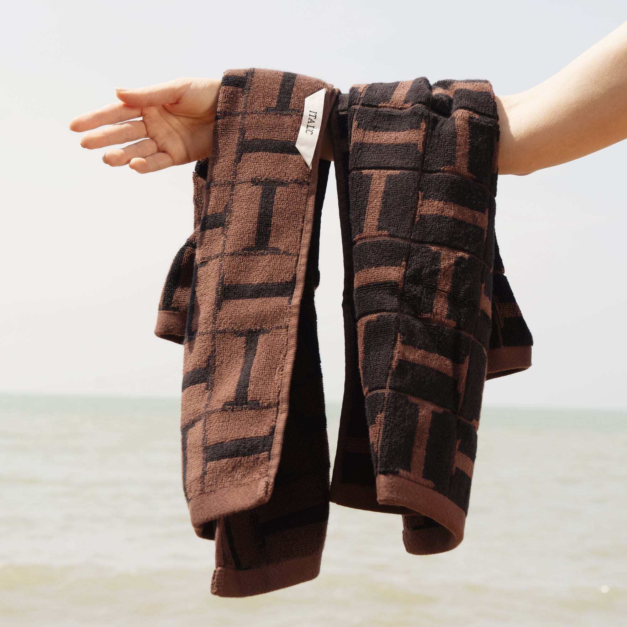 Brown and black geometric patterned plush spa towel with locker loop, soft 600 GSM Australian Cotton towels held by hand