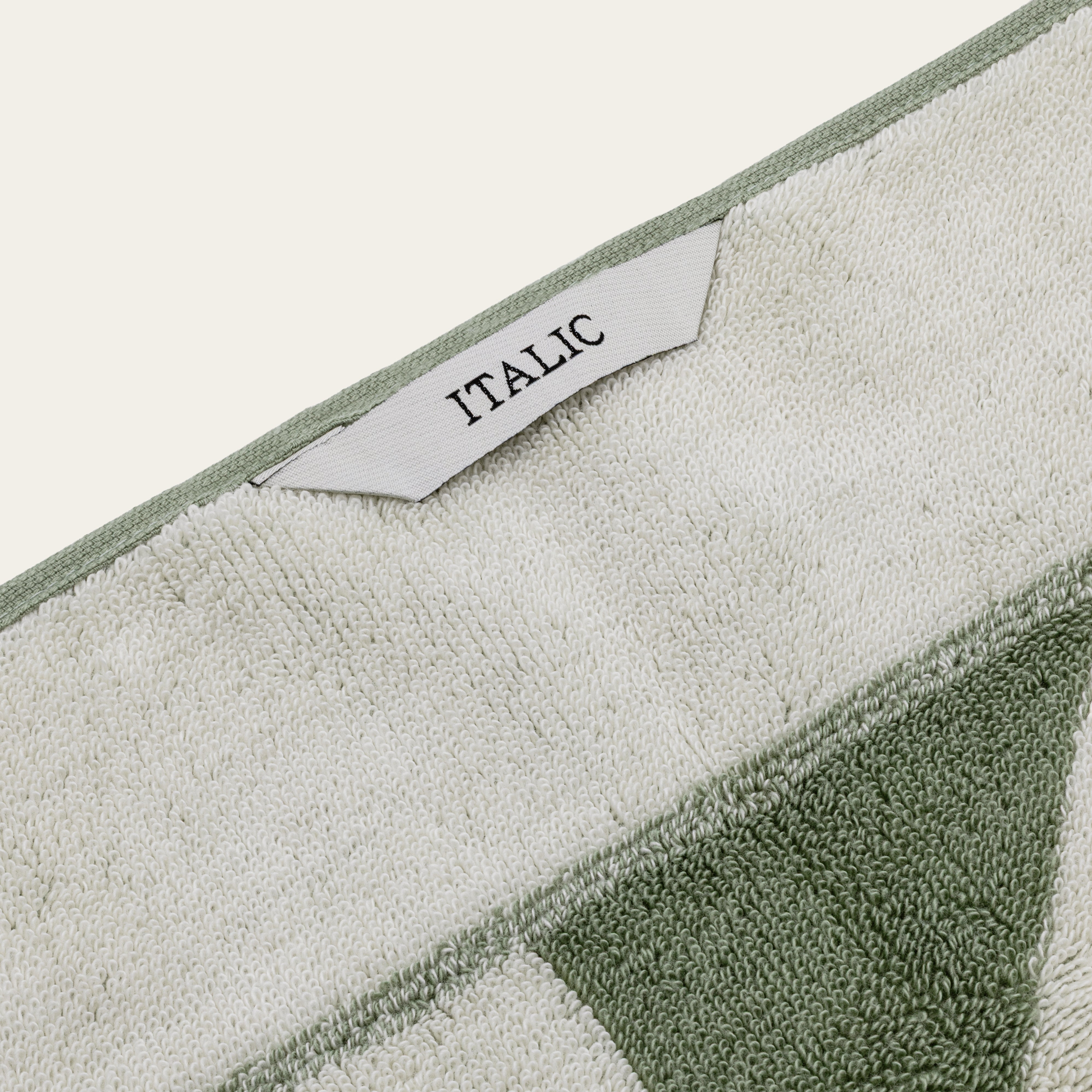 Australian Cotton Towels in cream and sage green, with a plush looped texture, geometric color blocks, and woven label