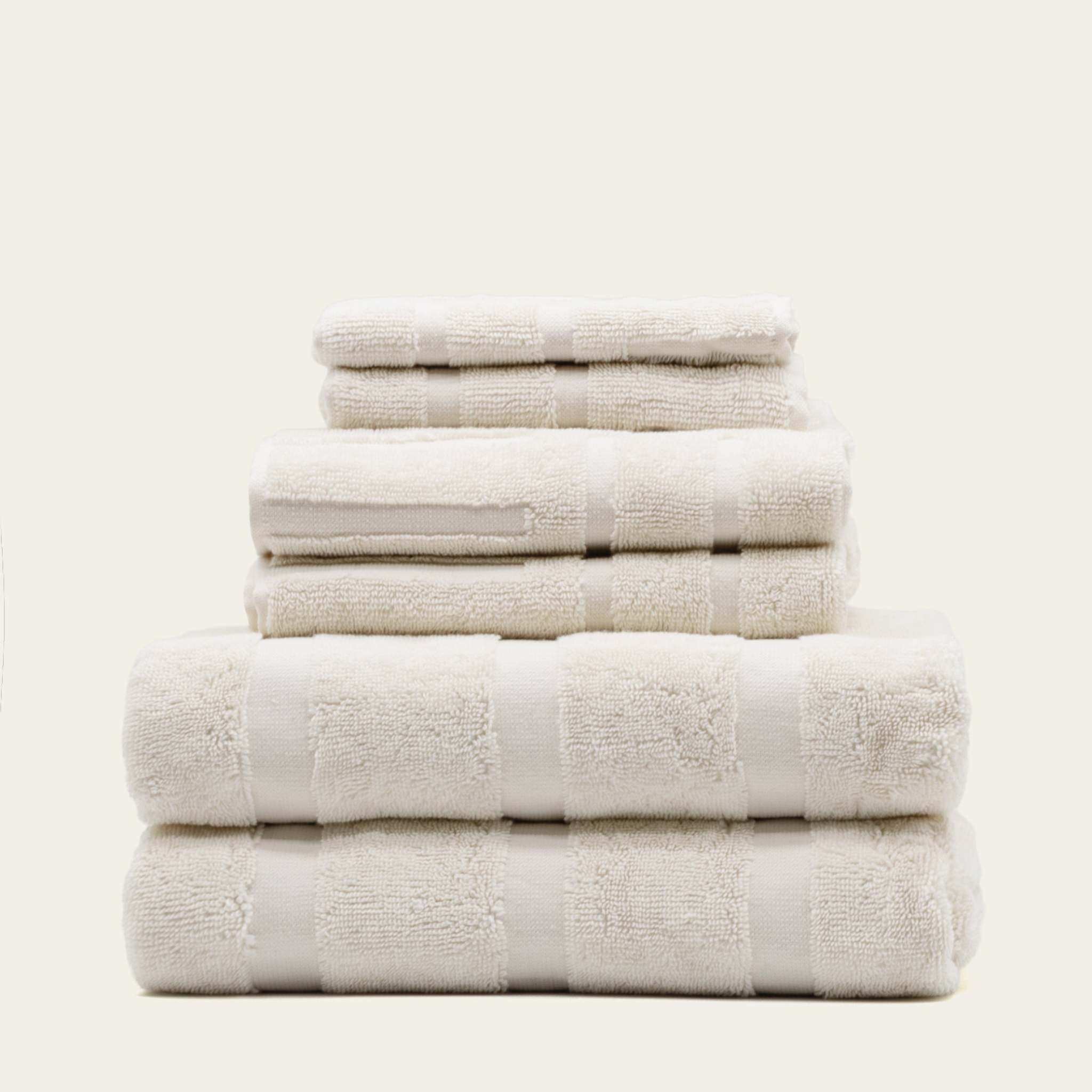 Australian Cotton towels in ecru color, plush 600 GSM cotton with subtle geometric textured pattern, stack of various towel sizes
