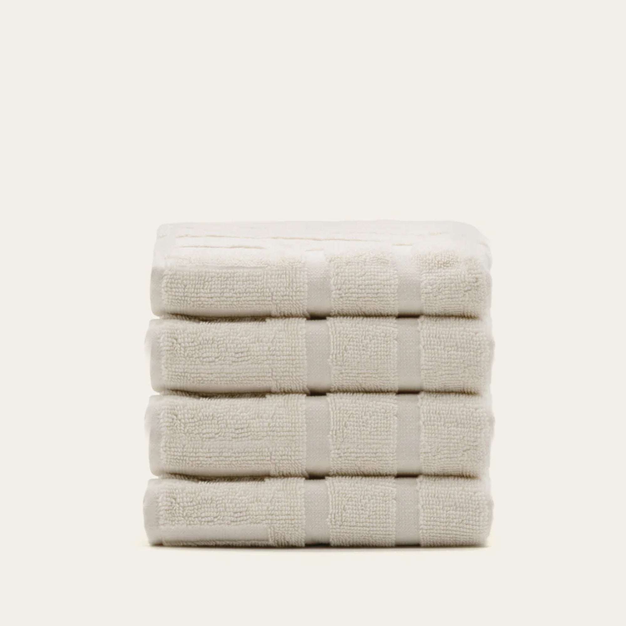 Stack of five soft ecru Australian Cotton towels with subtle horizontal textured stripes and plush finish