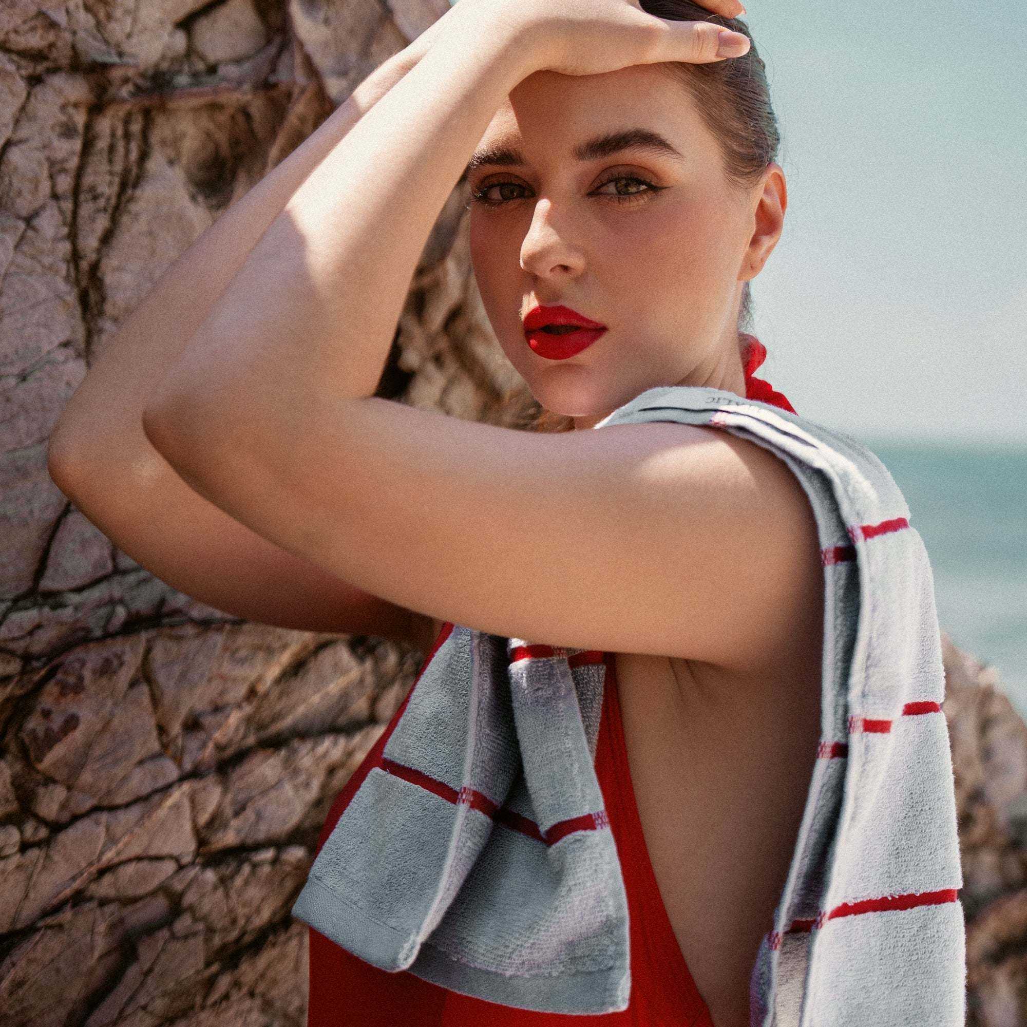 Australian Cotton towels in grey with red stripes draped over woman's shoulder, soft cotton texture visible