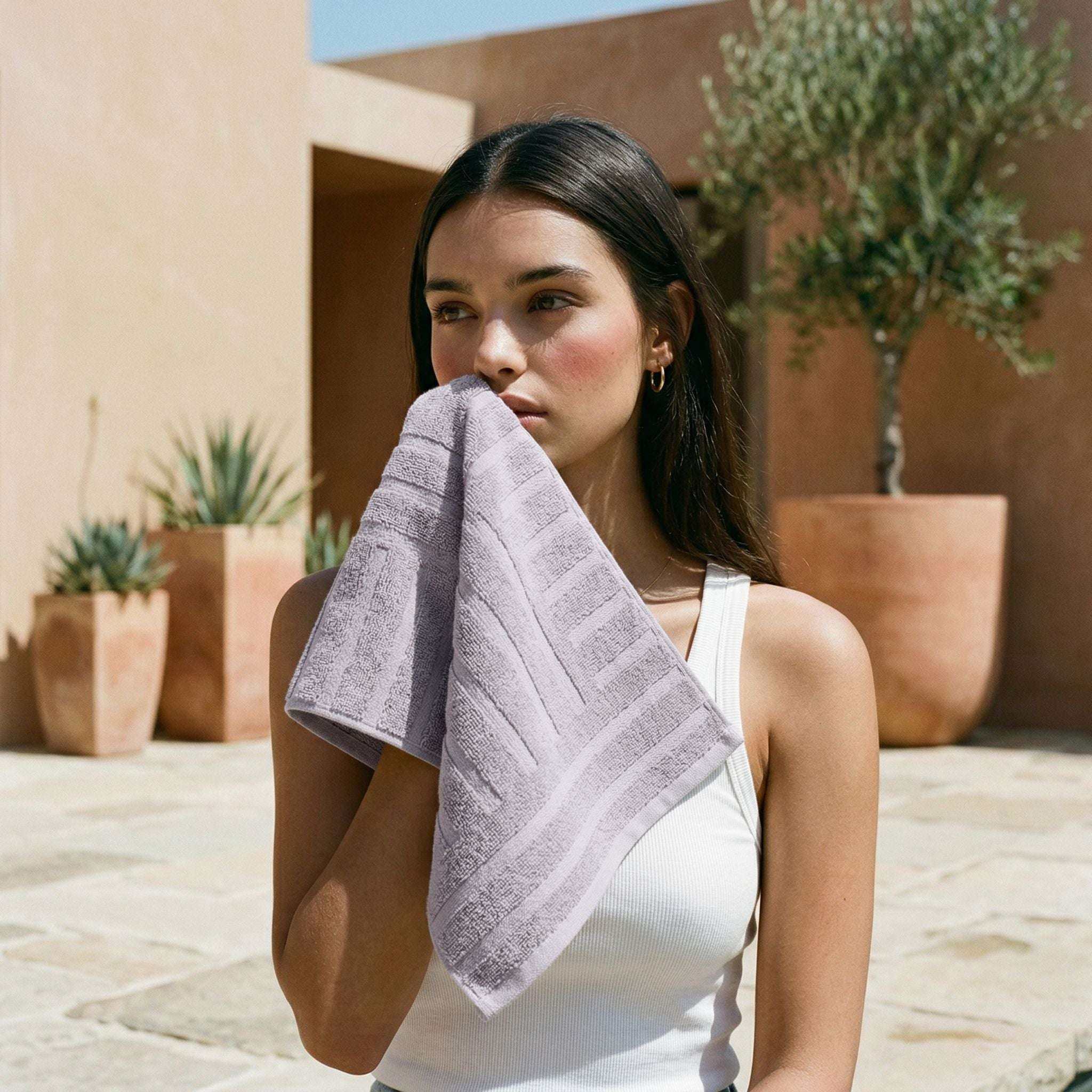 Australian Cotton towels in lilac with geometric patterns, plush and dense texture held by woman in white tank top