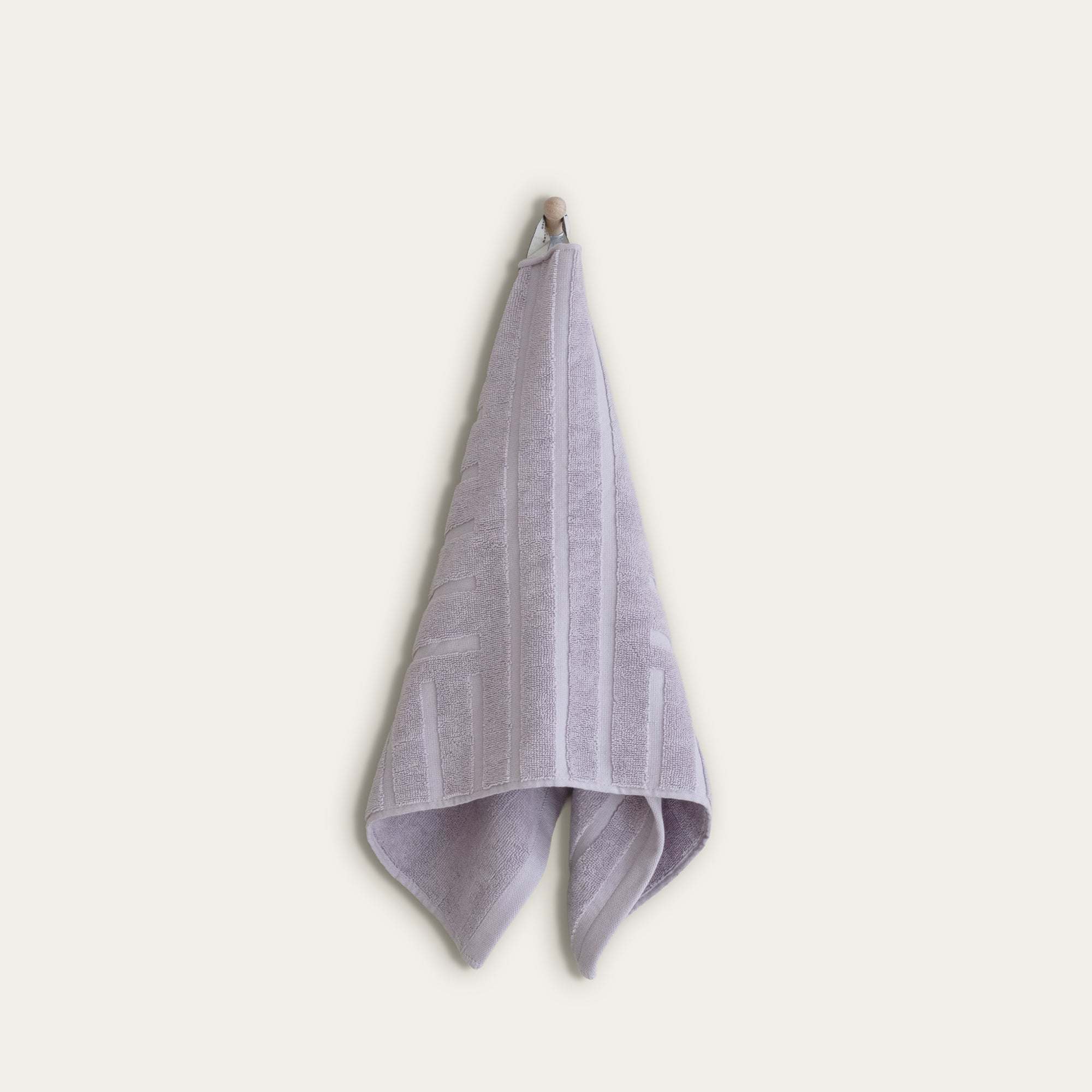 Australian Cotton towels in a soft lilac color with subtle geometric patterns and a functional locker loop hanging