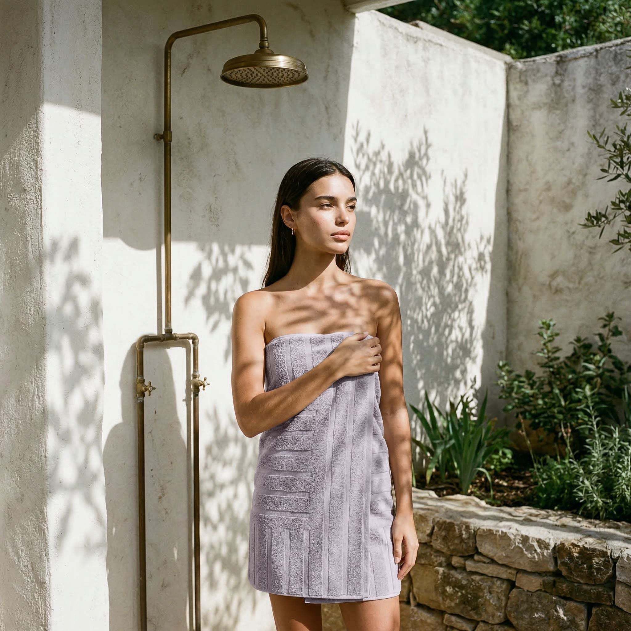 Australian Cotton towels in soft lilac with geometric patterns wrapped around a woman standing next to an outdoor shower