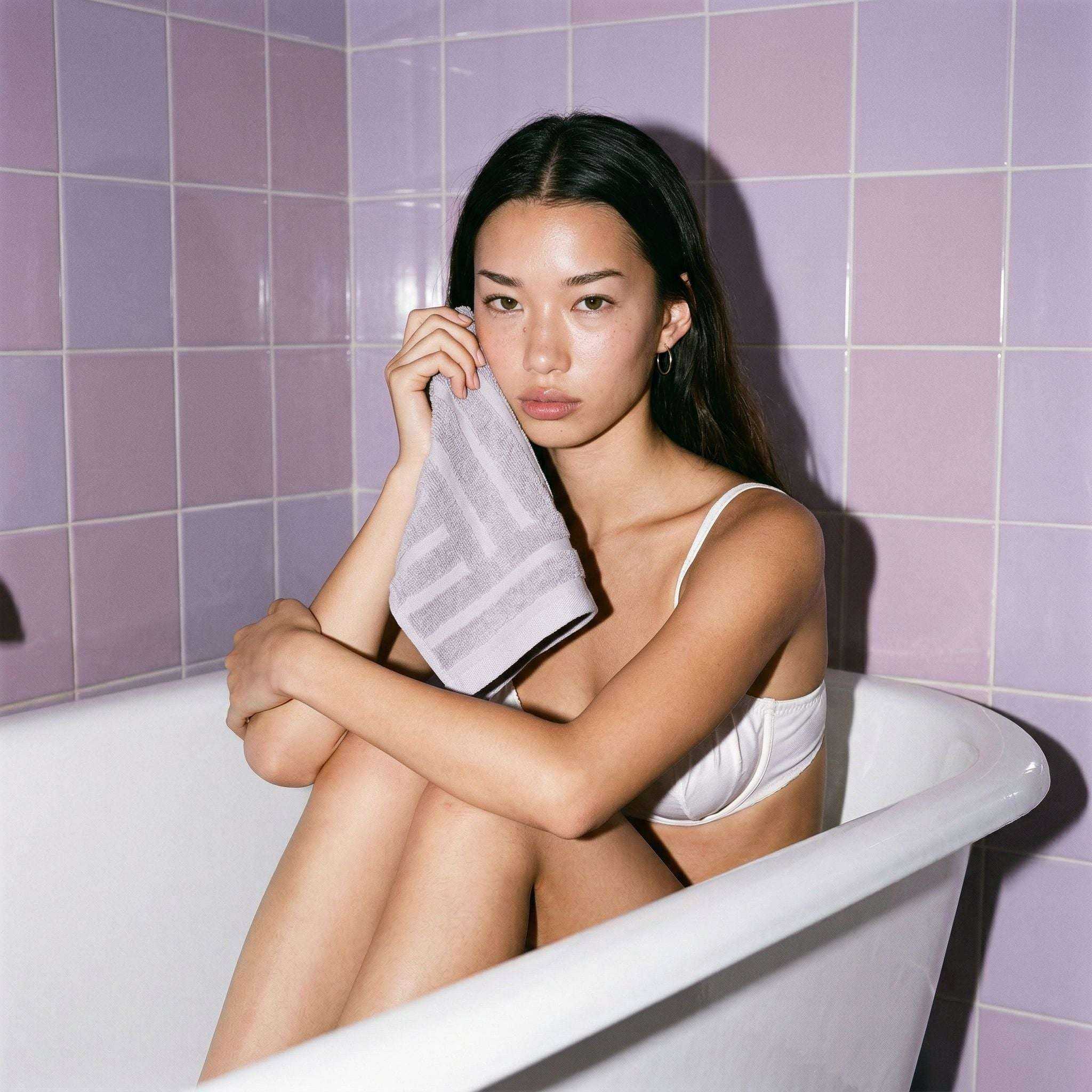 Australian Cotton towels soft lilac hand towel with geometric pattern held by woman sitting in white bathtub