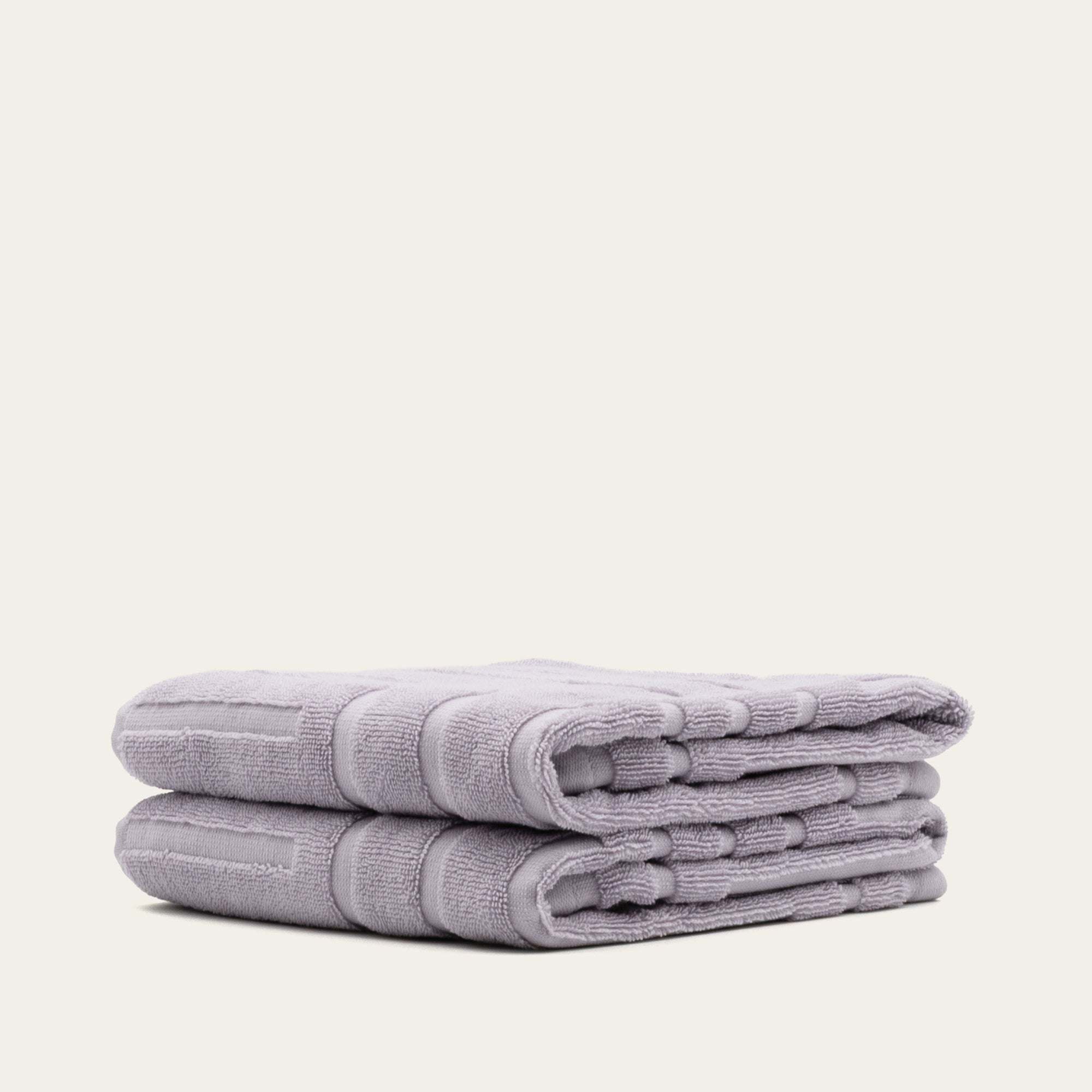 Stack of lilac Australian Cotton towels with a dense, plush texture and subtle geometric pattern detailing