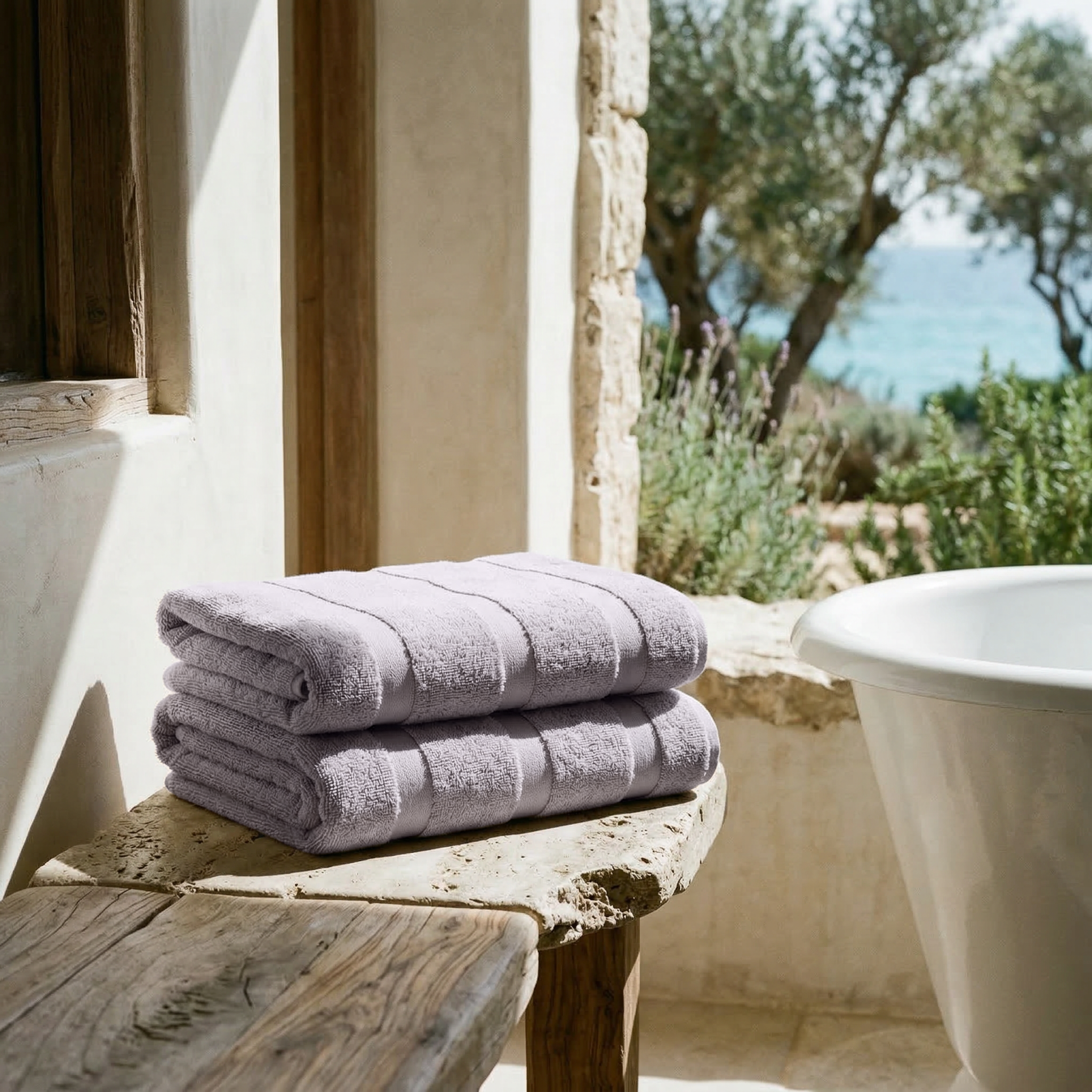 Stack of lilac Australian Cotton towels with soft plush texture and subtle stripes on a rustic wooden surface