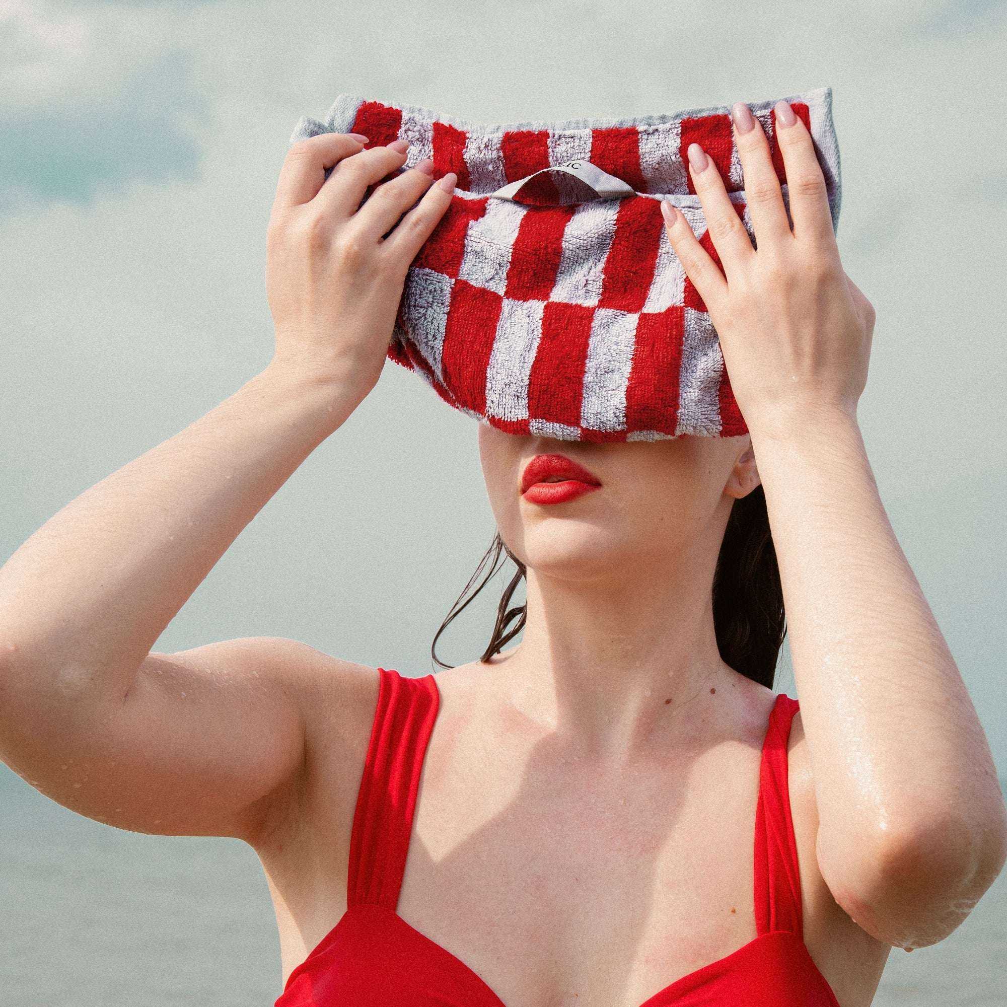 Australian Cotton towels with a bold red and white striped pattern made of plush cotton fabric held by a woman in a red swimsuit