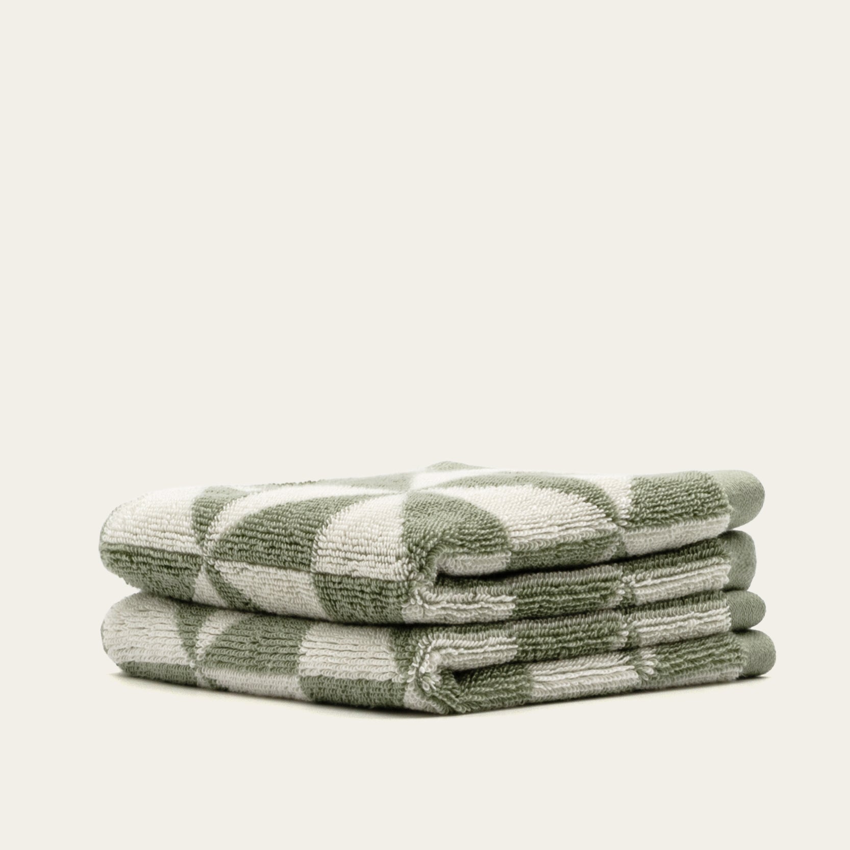 Australian Cotton Towels in a plush sage green and cream geometric check pattern, neatly stacked with looped terry texture