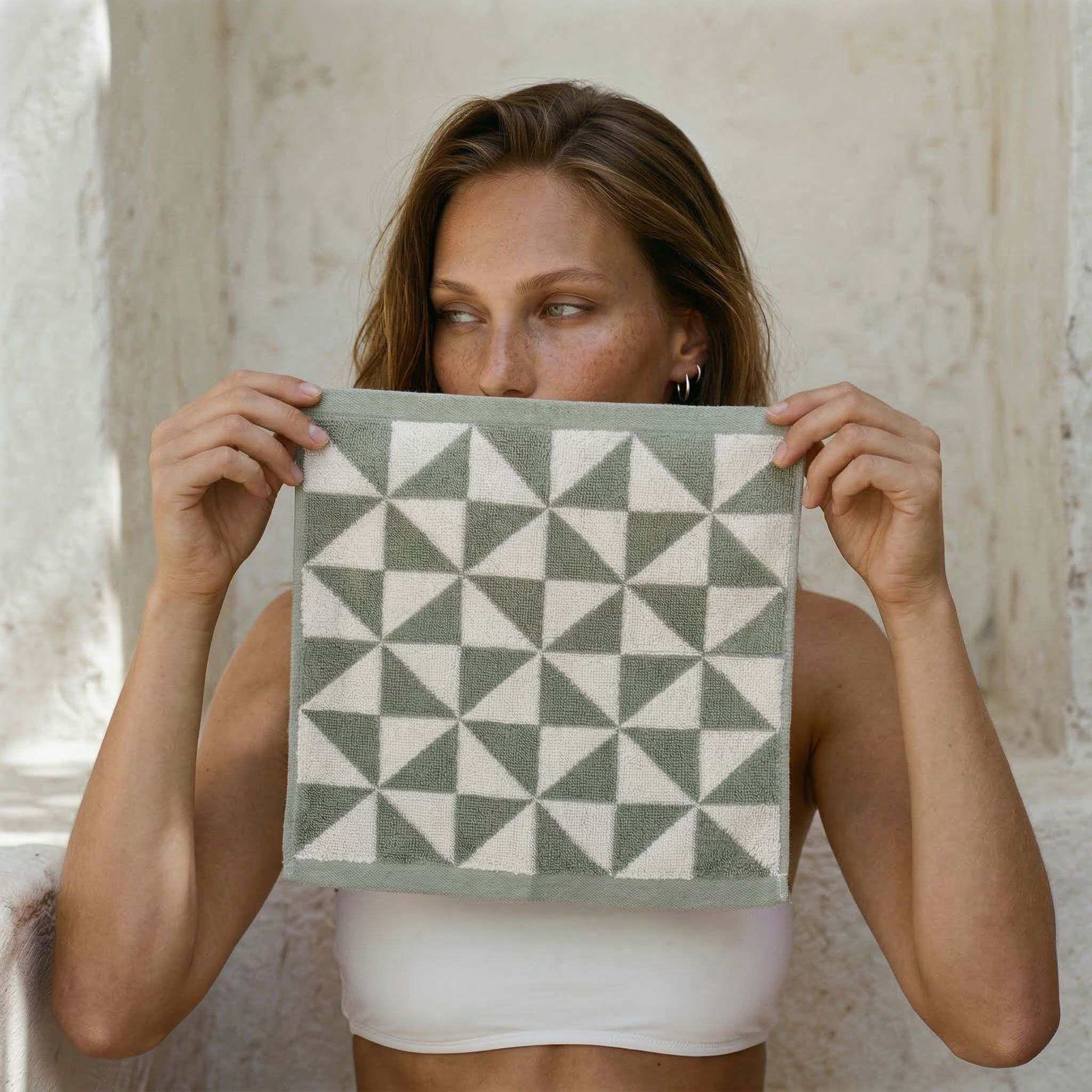 Australian Cotton towels in sage and ecru geometric pattern, ultra-soft 600 GSM cotton washcloth held by woman