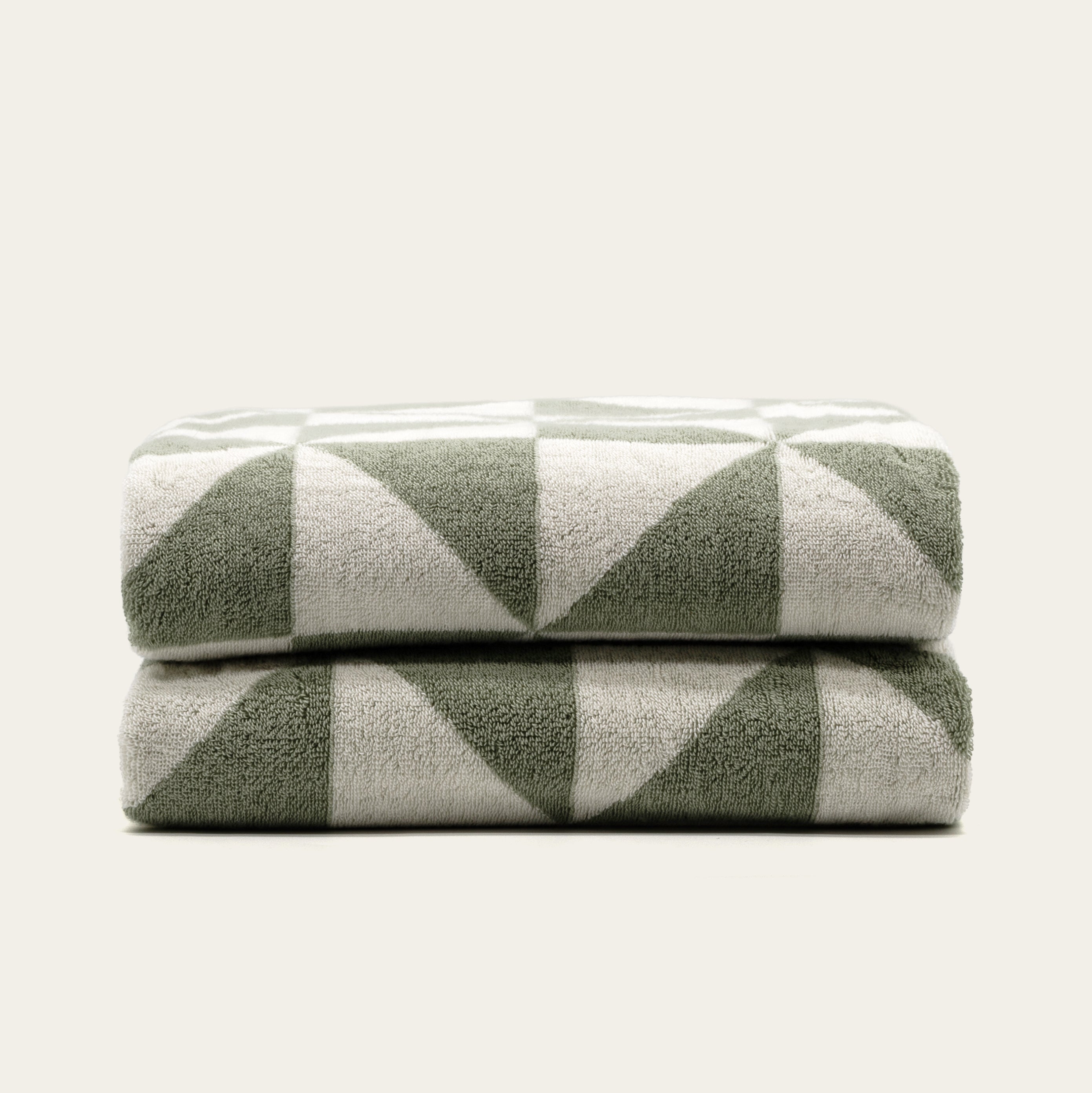 Australian Cotton Towels in plush sage green and cream cotton with a bold geometric triangular pattern, folded in a stack
