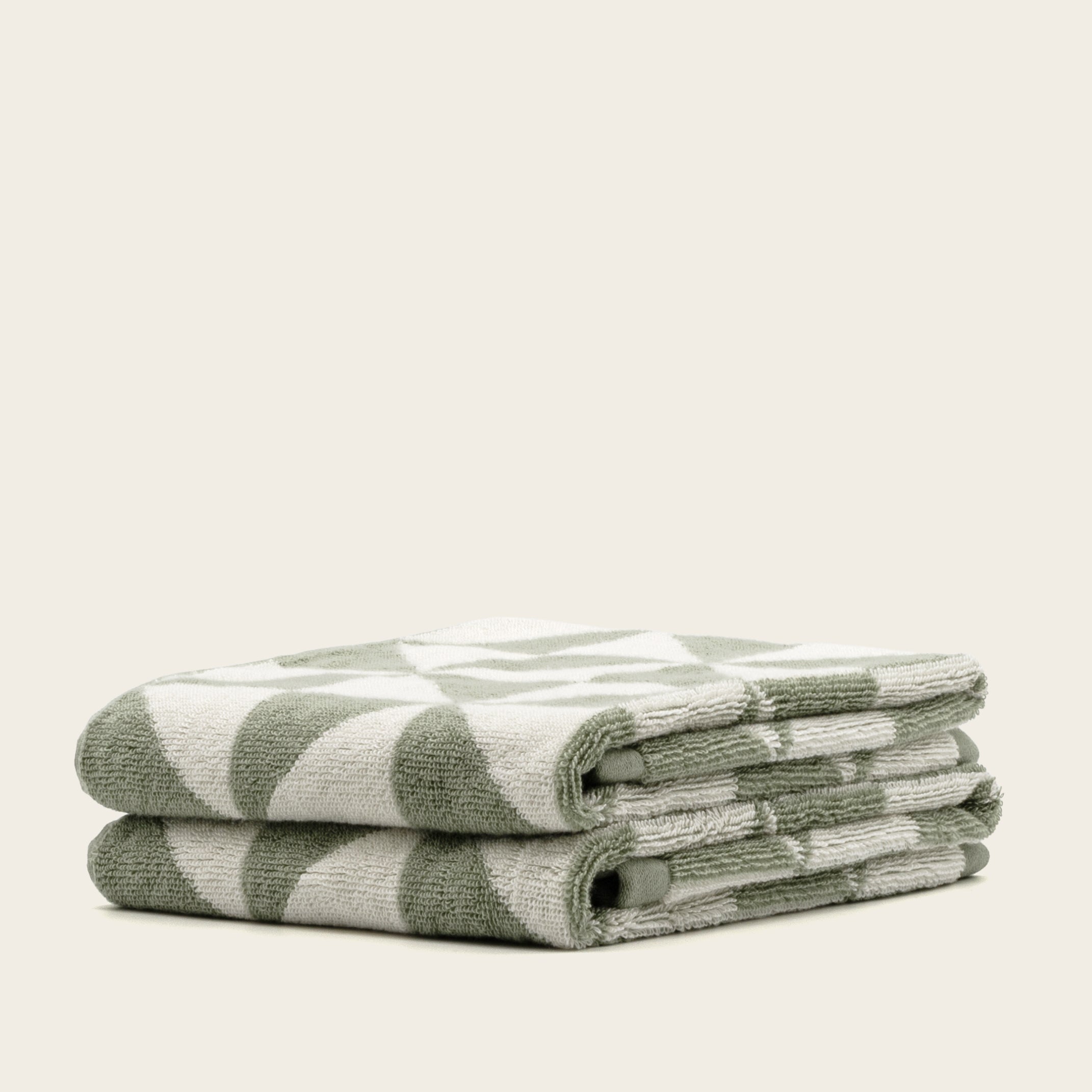 Australian Cotton Towels in muted sage green and cream, plush woven cotton with a bold geometric triangular pattern
