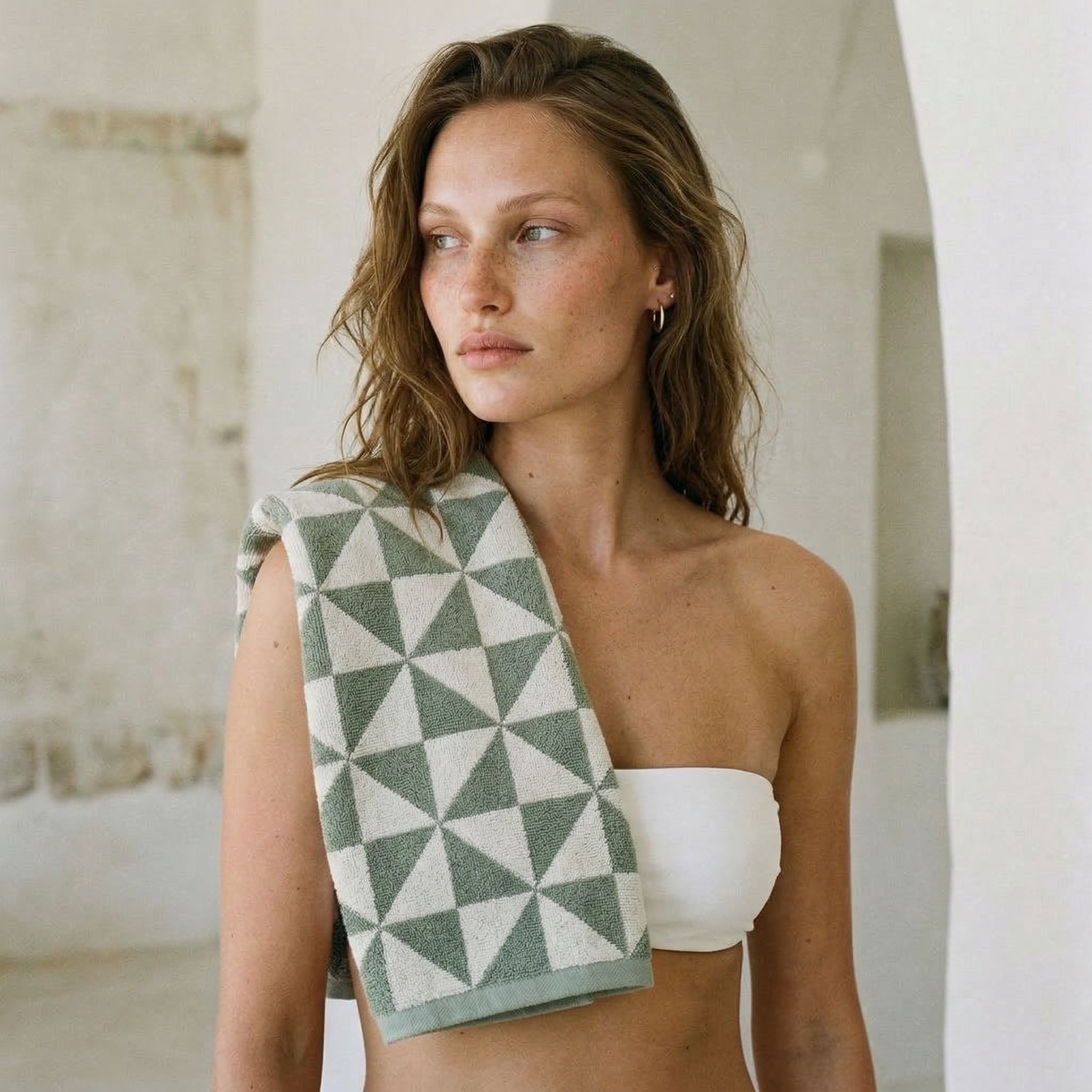 Australian Cotton Towels in sage green and cream, featuring a plush woven triangular pattern draped over a shoulder