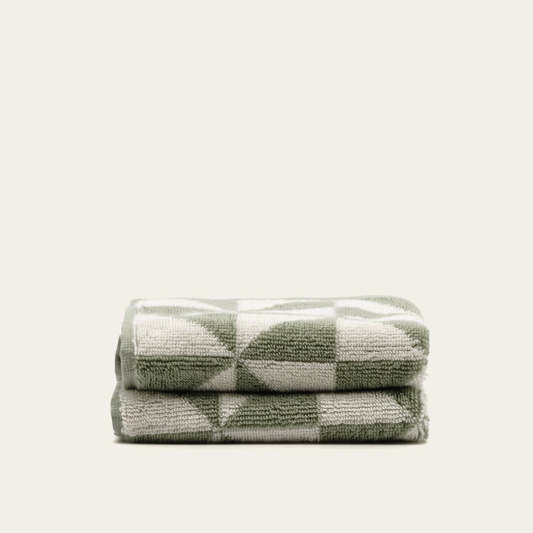 Australian Cotton Towels in sage green and cream cotton terry, folded with a bold geometric triangular pattern