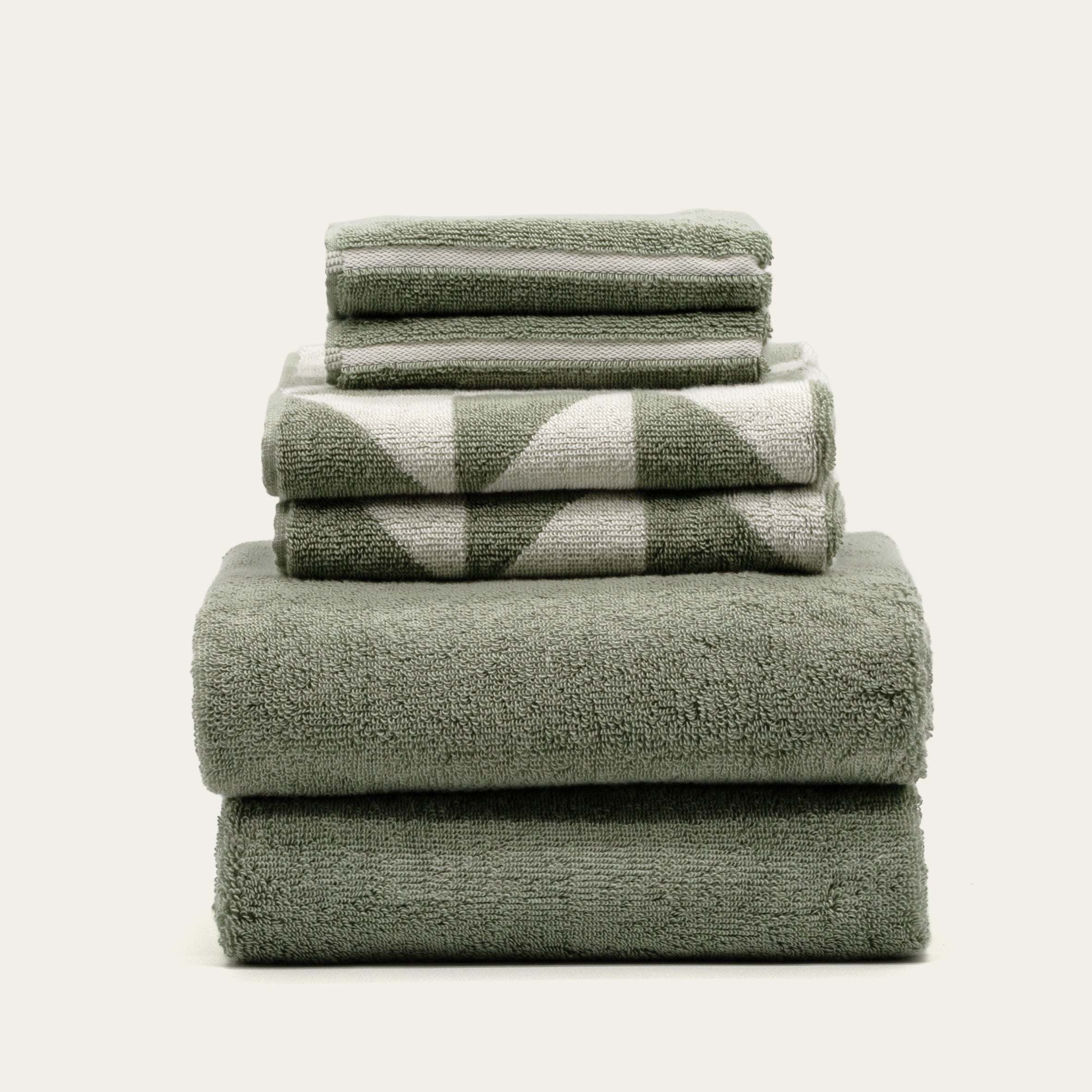 Australian Cotton Towels in muted sage green terry cotton, stacked with a bold white triangular pattern on two pieces
