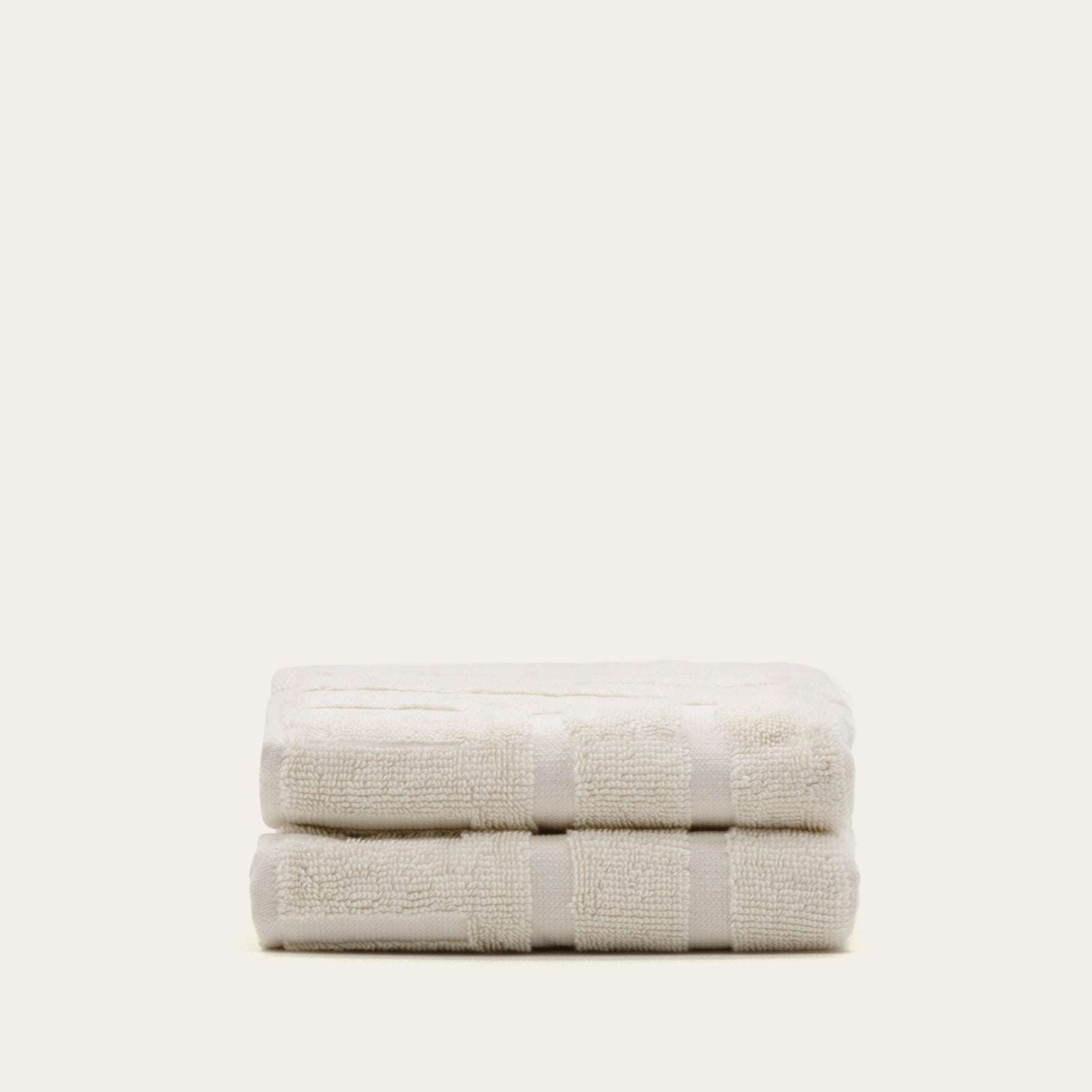 Set of soft ecru Australian Cotton towels with geometric pattern and dense texture neatly stacked