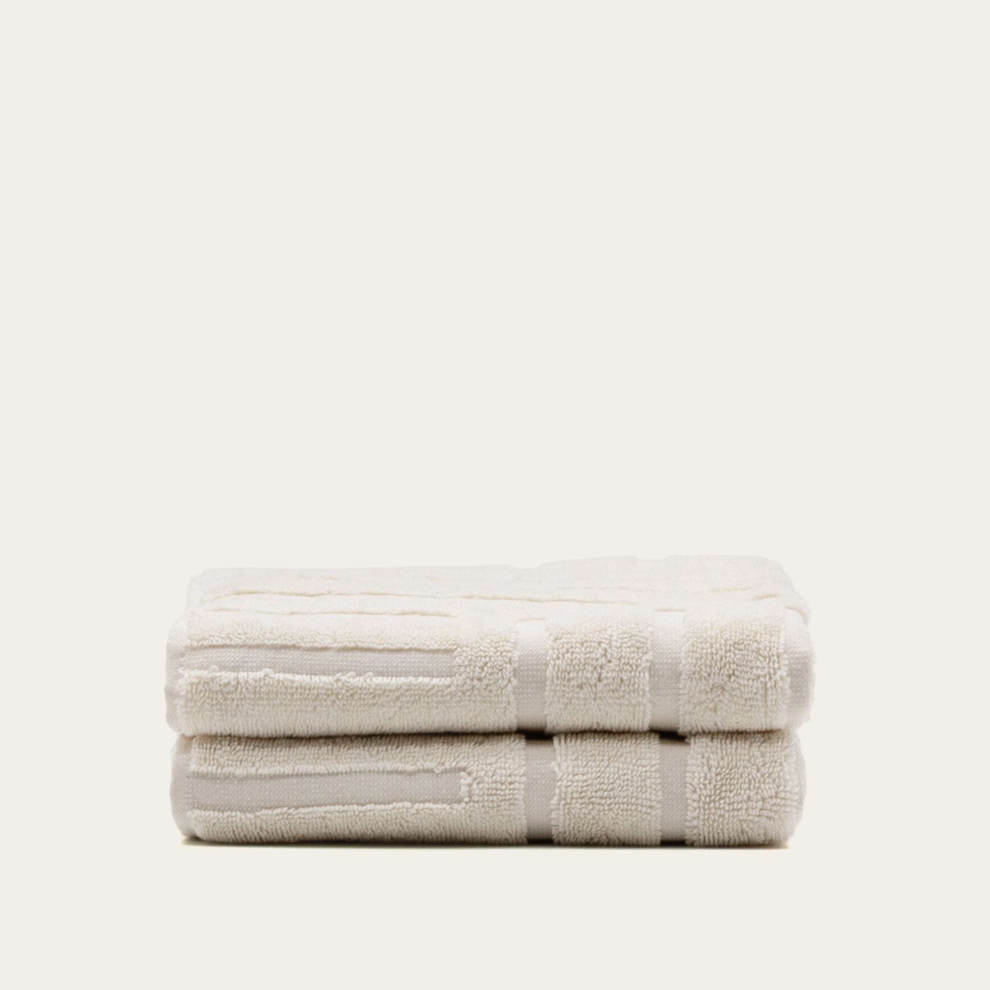 Set of two soft ecru Australian Cotton towels with a subtle geometric pattern and plush texture
