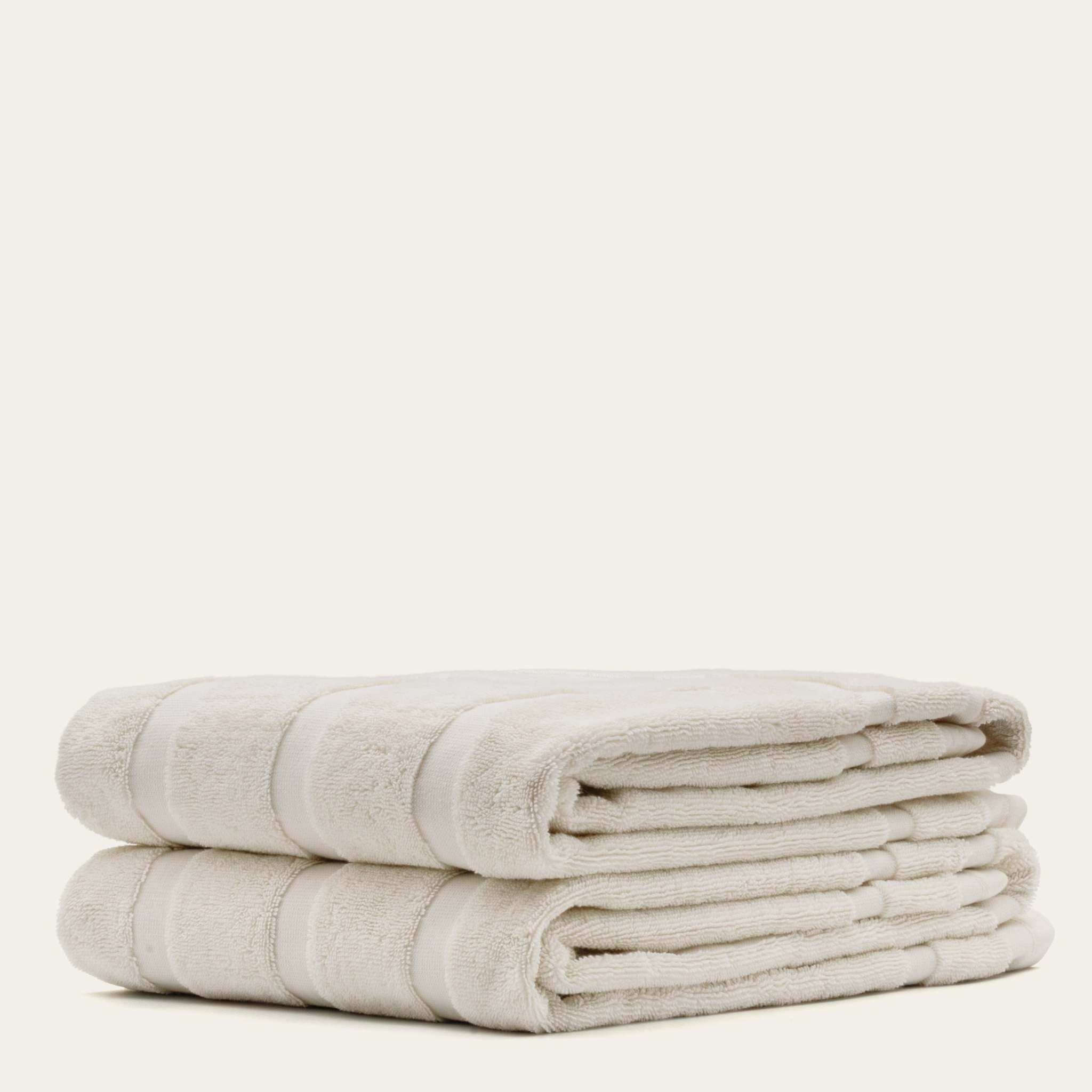 Australian Cotton towels in soft ecru color, plush cotton material with subtle striped texture, folded neatly