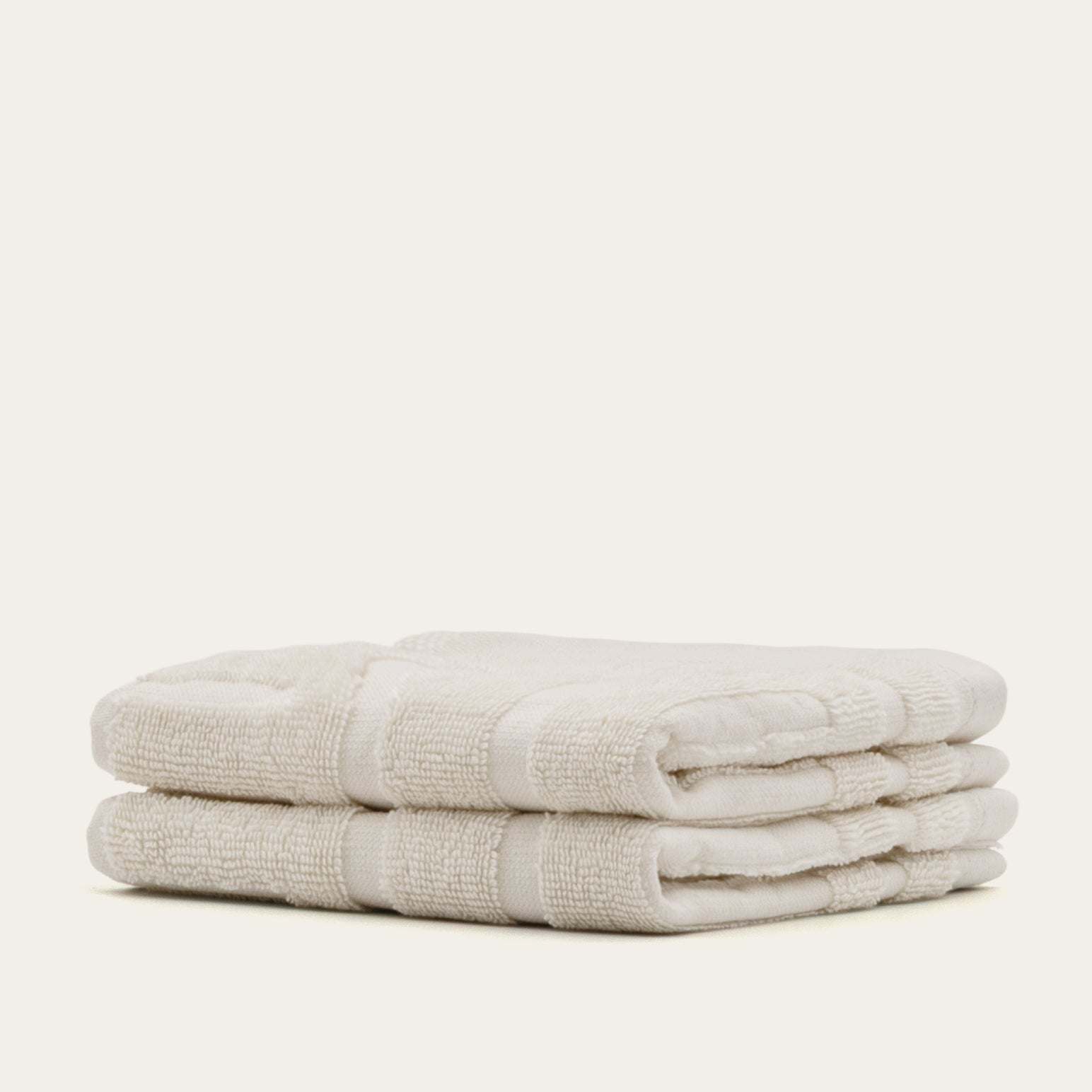 Stack of soft ecru Australian Cotton towels with textured geometric patterns and plush 600 GSM cotton material