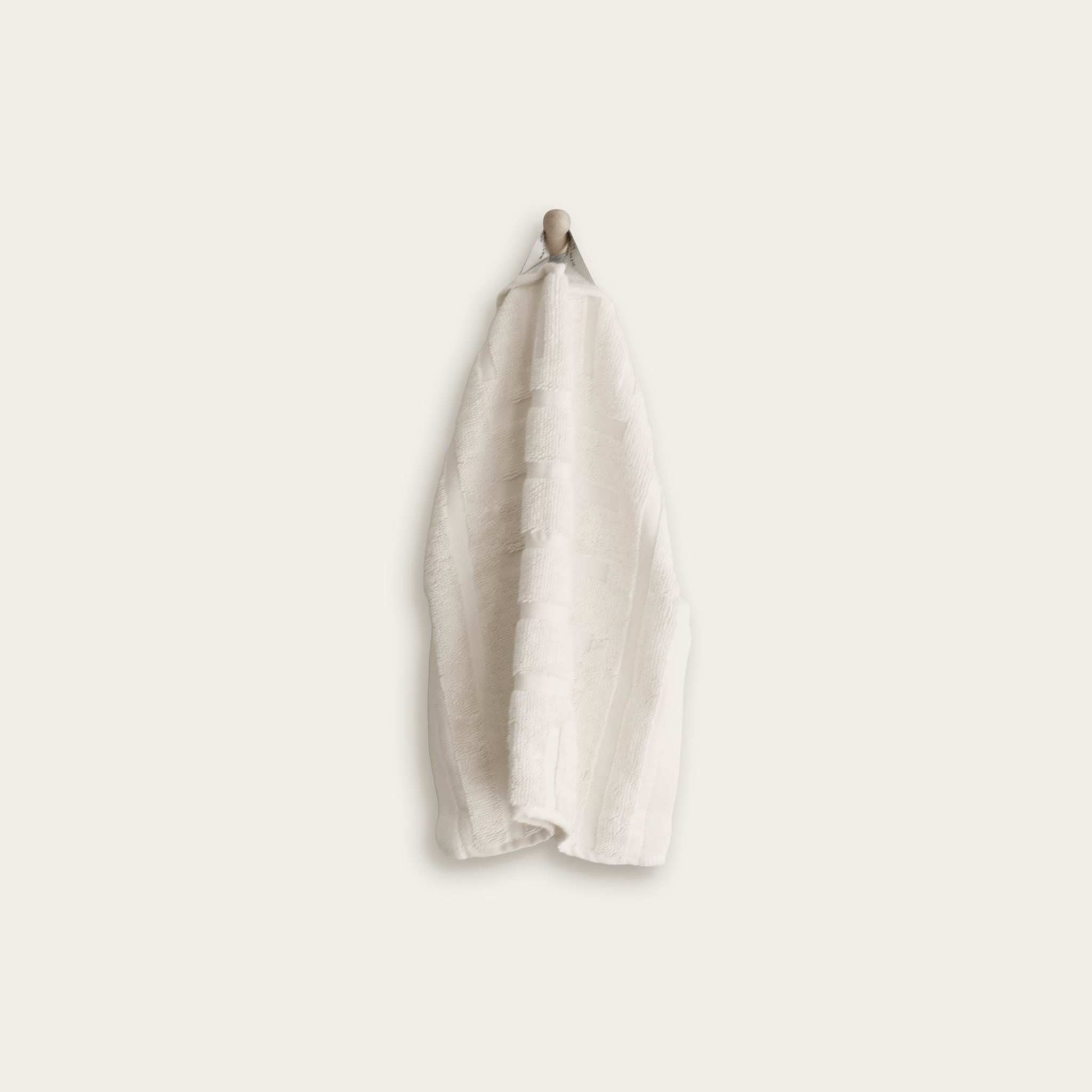 White Australian Cotton towels with geometric pattern and a hanging loop against a plain background