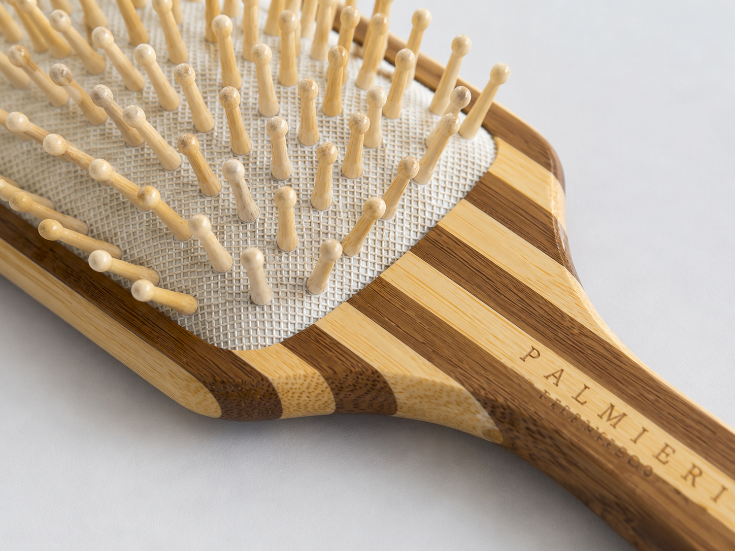 Bamboo Hairbrush with a striped natural wood handle, light rounded bristles, and a white mesh cushion