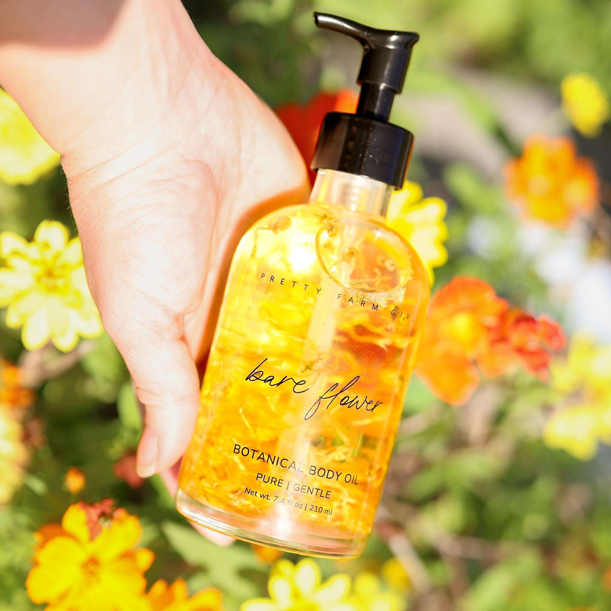 Bare Flower Fragrance-Free Body Oil in a clear glass pump bottle, golden botanical-infused oil with flower petals