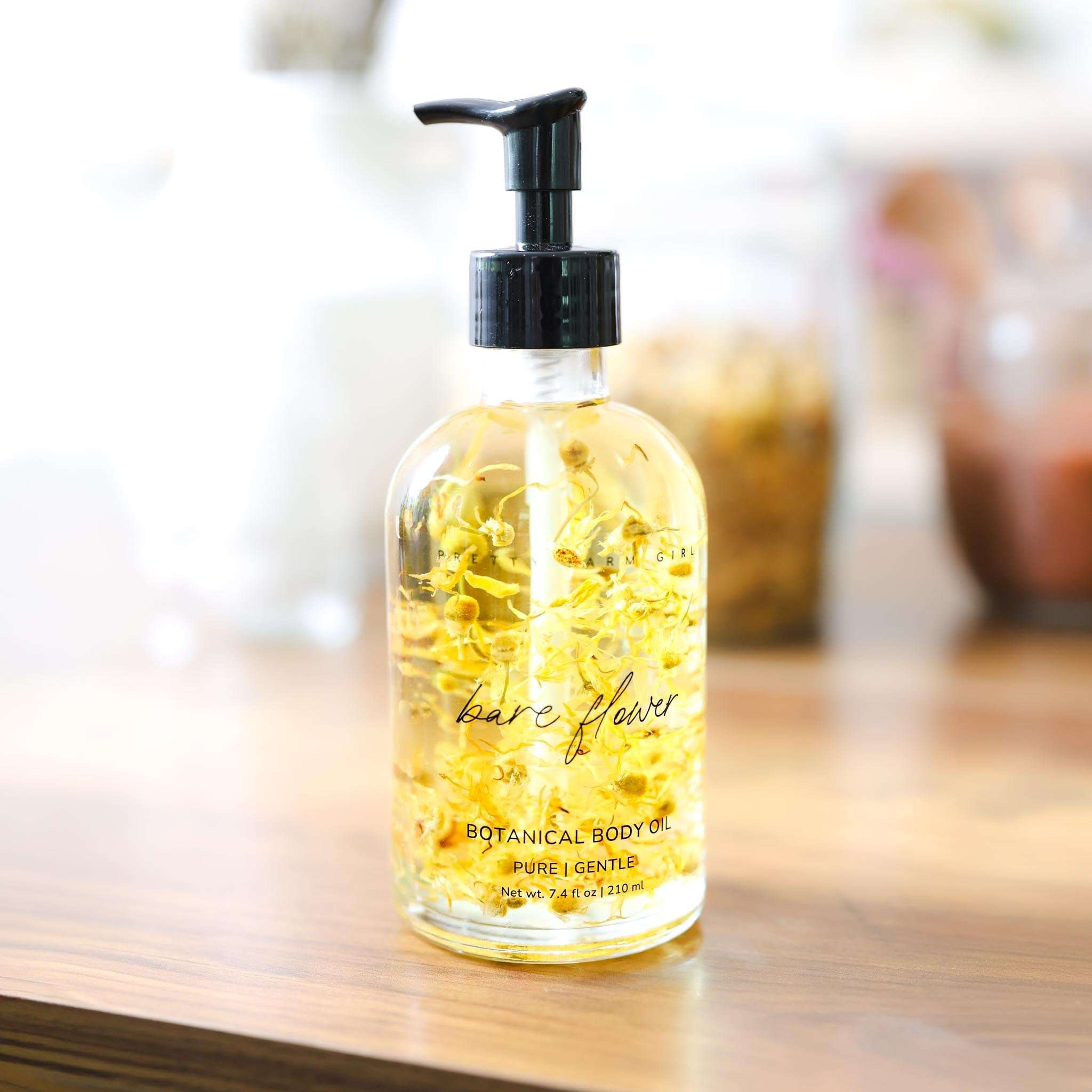Bare Flower Fragrance-Free Body Oil in a clear glass pump bottle with golden botanical-infused oil and flowers