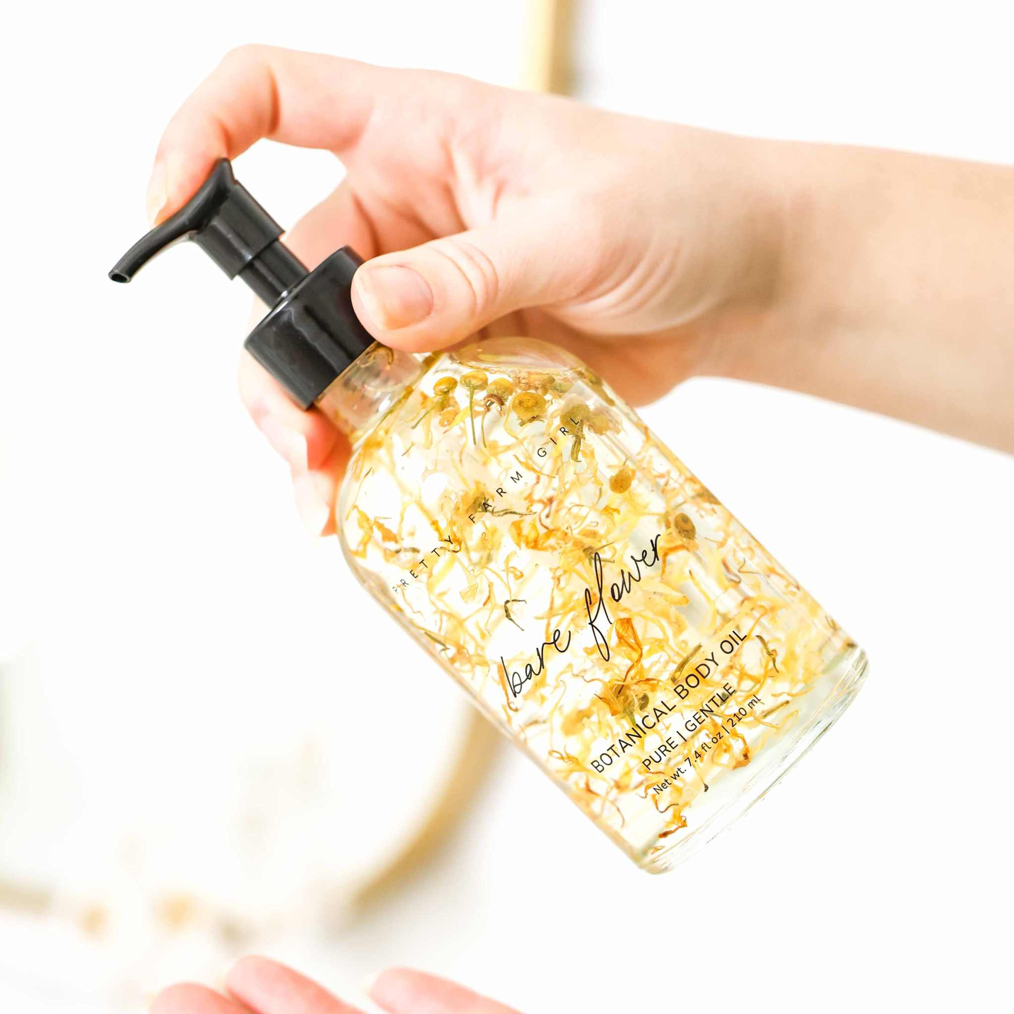 Bare Flower Fragrance-Free Body Oil in a clear glass pump bottle with golden botanical flower infusion