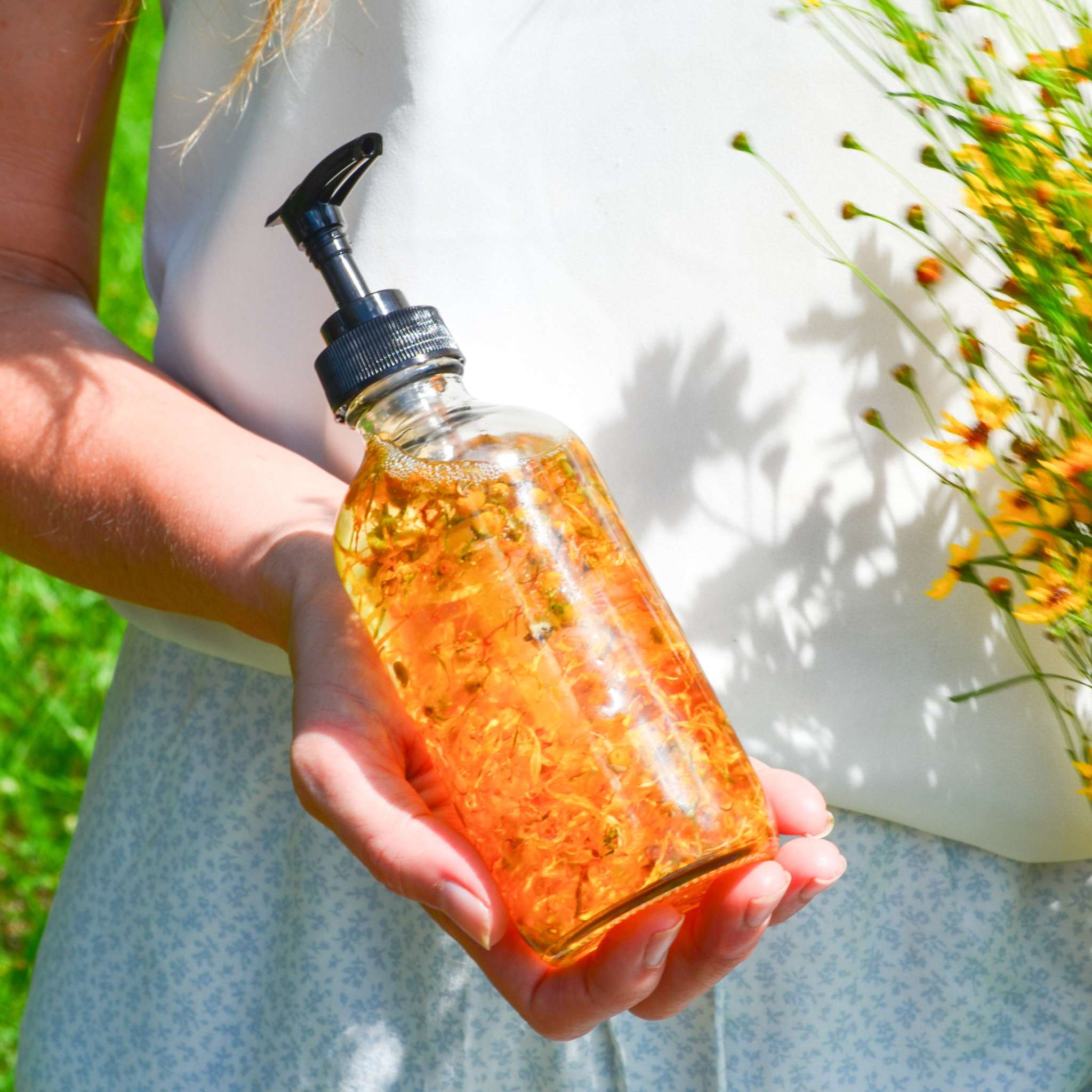 Bare Flower Fragrance-Free Body Oil in a clear glass pump bottle, filled with golden botanical-infused oil