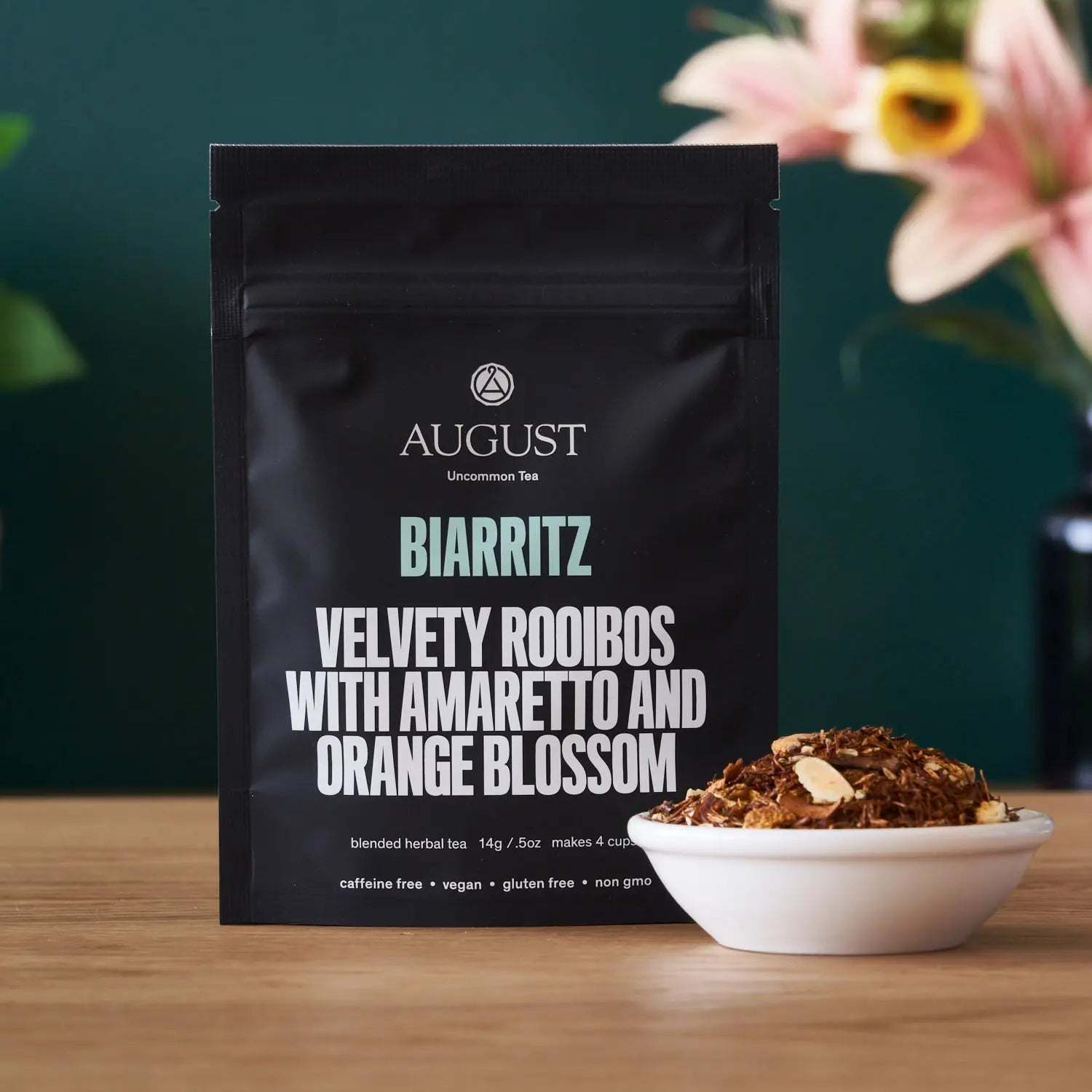 Biarritz - Orange Amaretto Rooibos Tea in a black matte pouch with a bowl of loose rooibos tea
