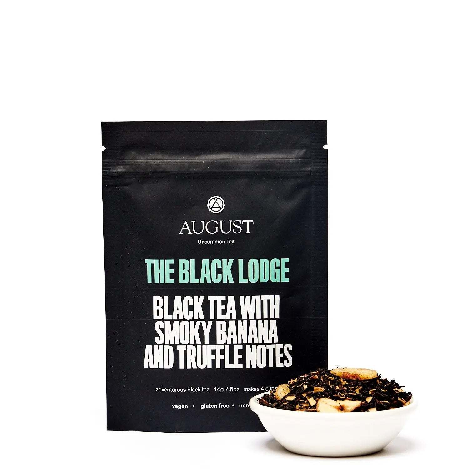 Black Lodge - Smoky Banana Black Tea in a black pouch with a bowl of loose dark tea and visible banana pieces