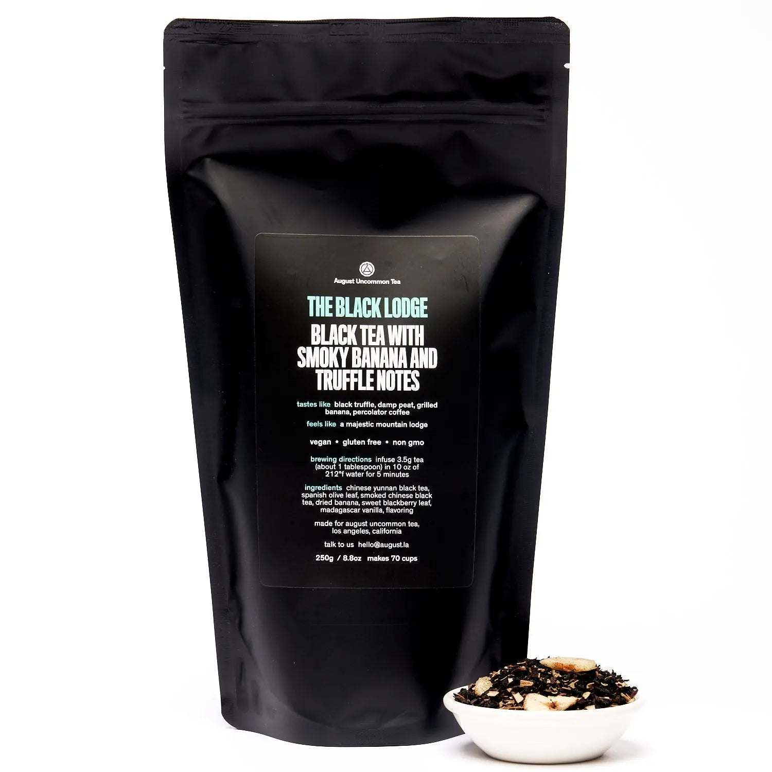 Black tea pouch, Black Lodge - Smoky Banana Black Tea, in matte black packaging with a bowl of loose tea leaves