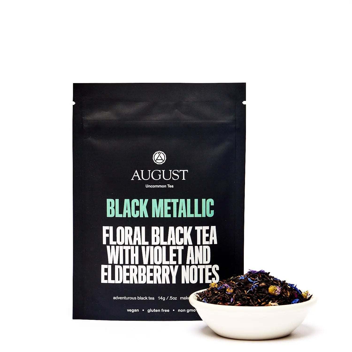 Black Metallic - Violet Elderberry Black Tea in a matte black pouch with a bowl of loose dark tea leaves and flowers
