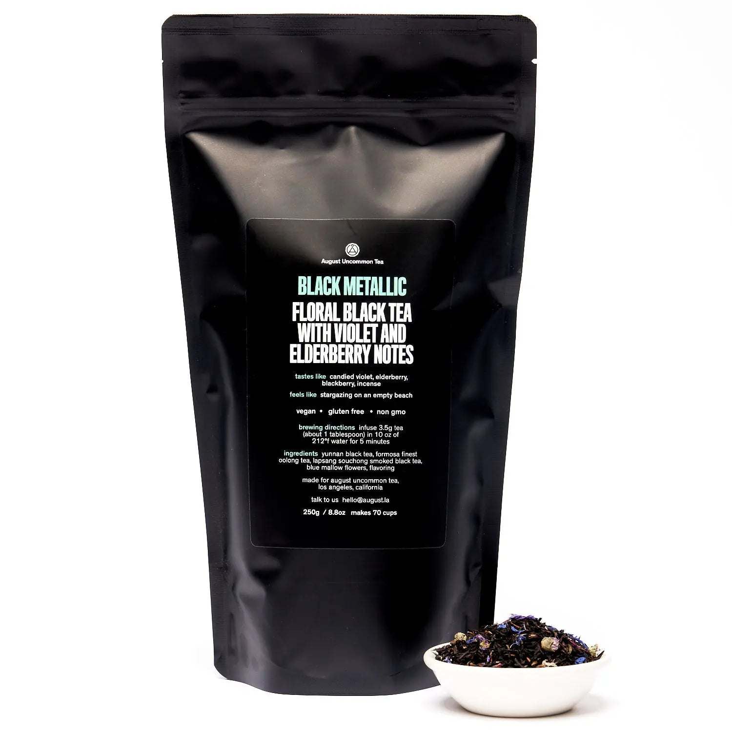 Black Metallic - Violet Elderberry Black Tea in a glossy black resealable pouch with a bowl of loose floral tea