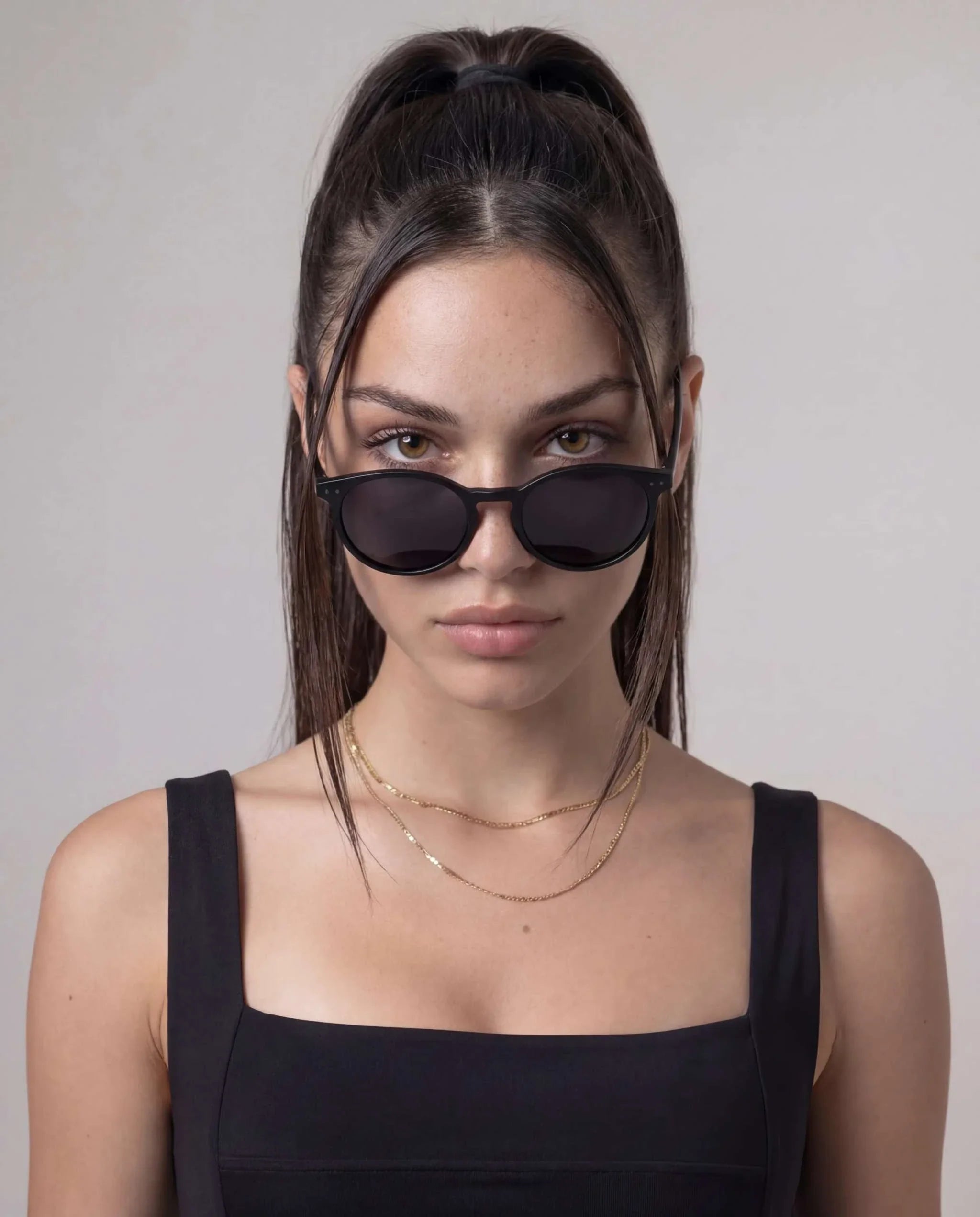Black Round Polarized Sunglasses with a glossy black frame, dark round lenses, and slim temples worn by a woman