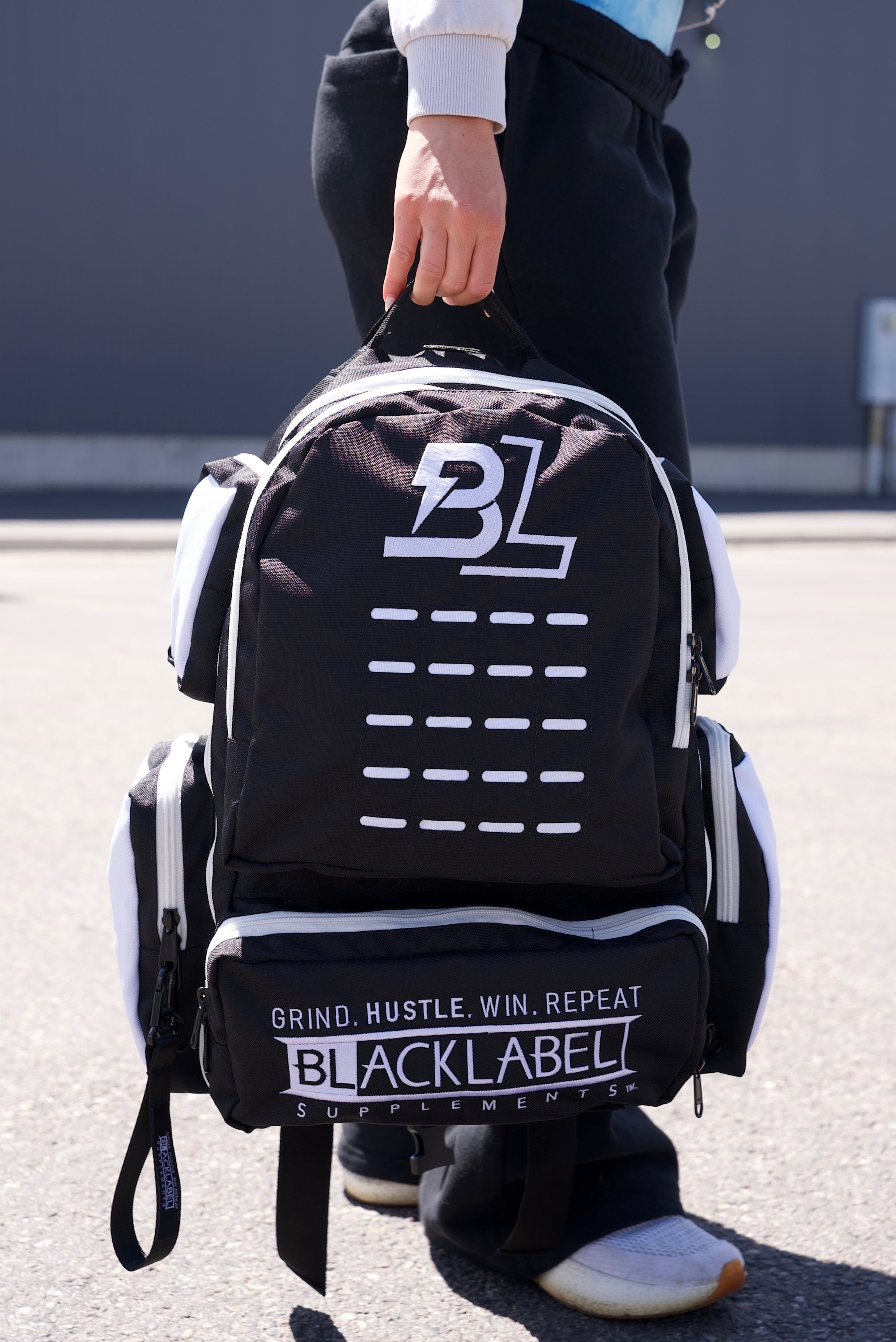BlackLabel 26L BackPack in black nylon with white trim, bold front logo, horizontal accents, and multiple zip compartments