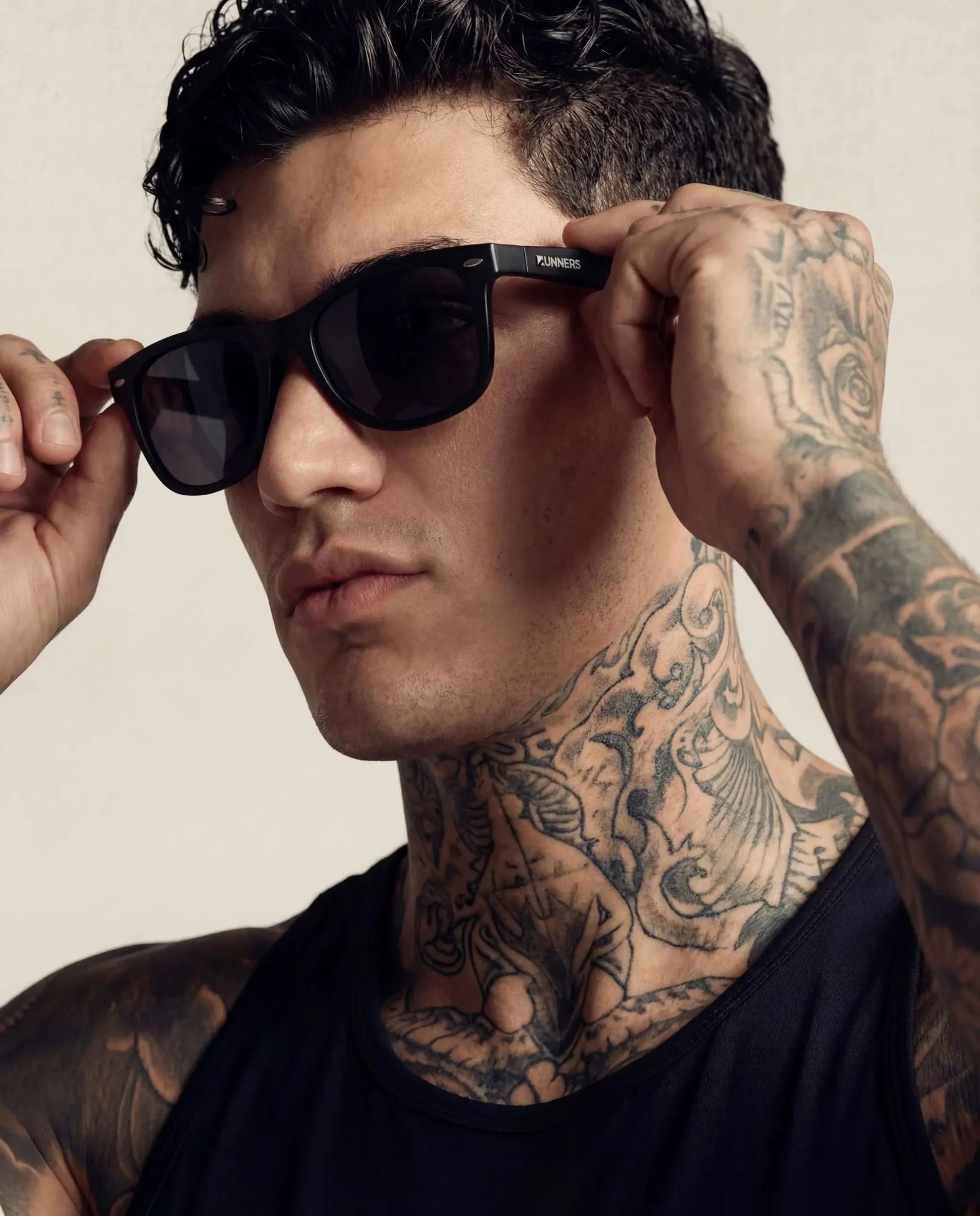 Blackout Square Running Sunglasses with glossy black frames and dark lenses, shown being worn by a man