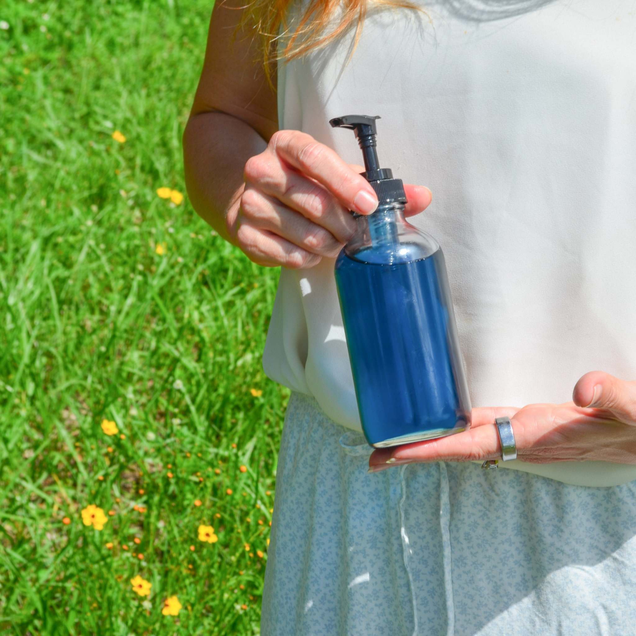 Blue Bloom Botanical Body Oil in a deep blue glass bottle with a black plastic pump dispenser
