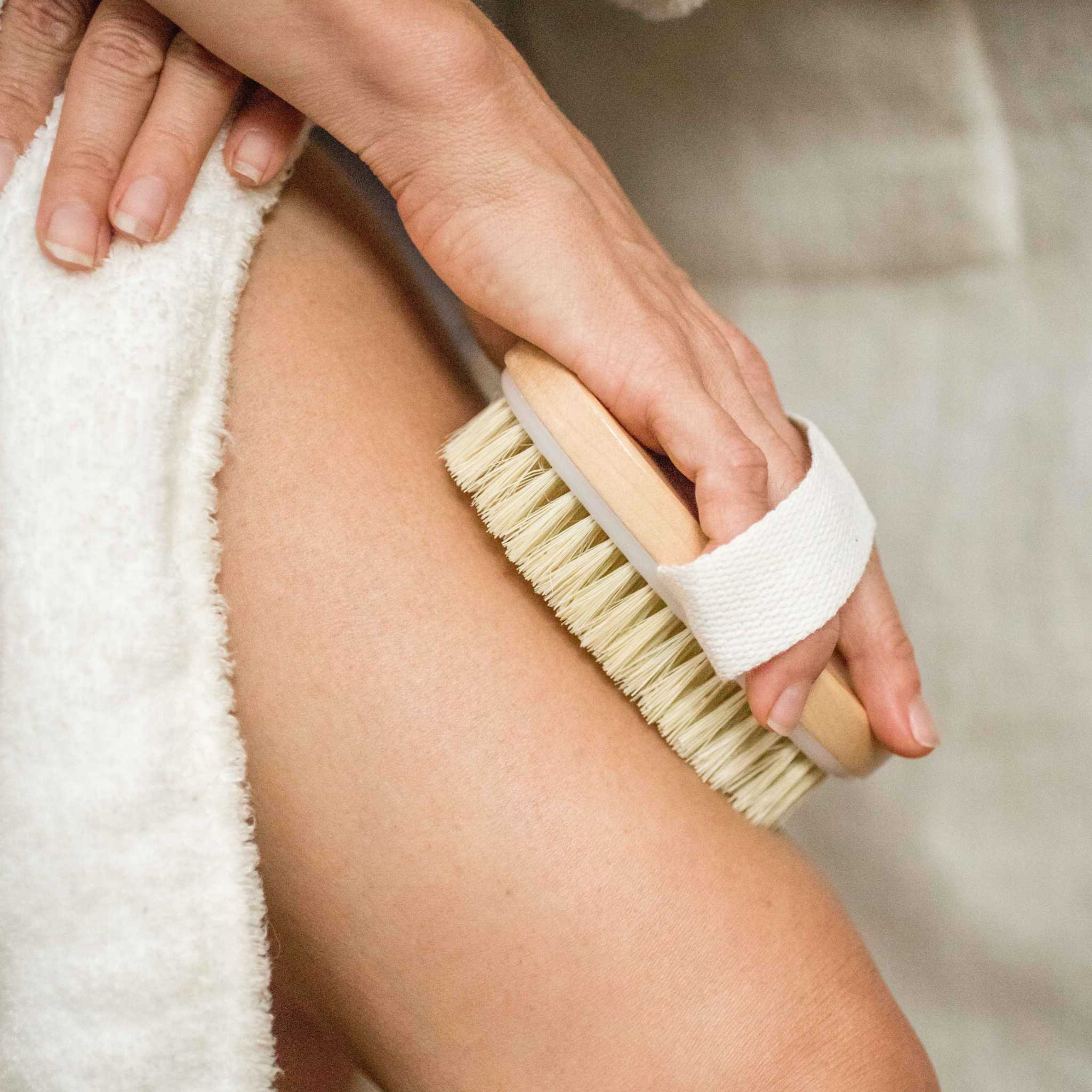 Body Care Lymphatic Routine Kit featuring a natural bamboo and sisal dry brush with white cotton strap on skin