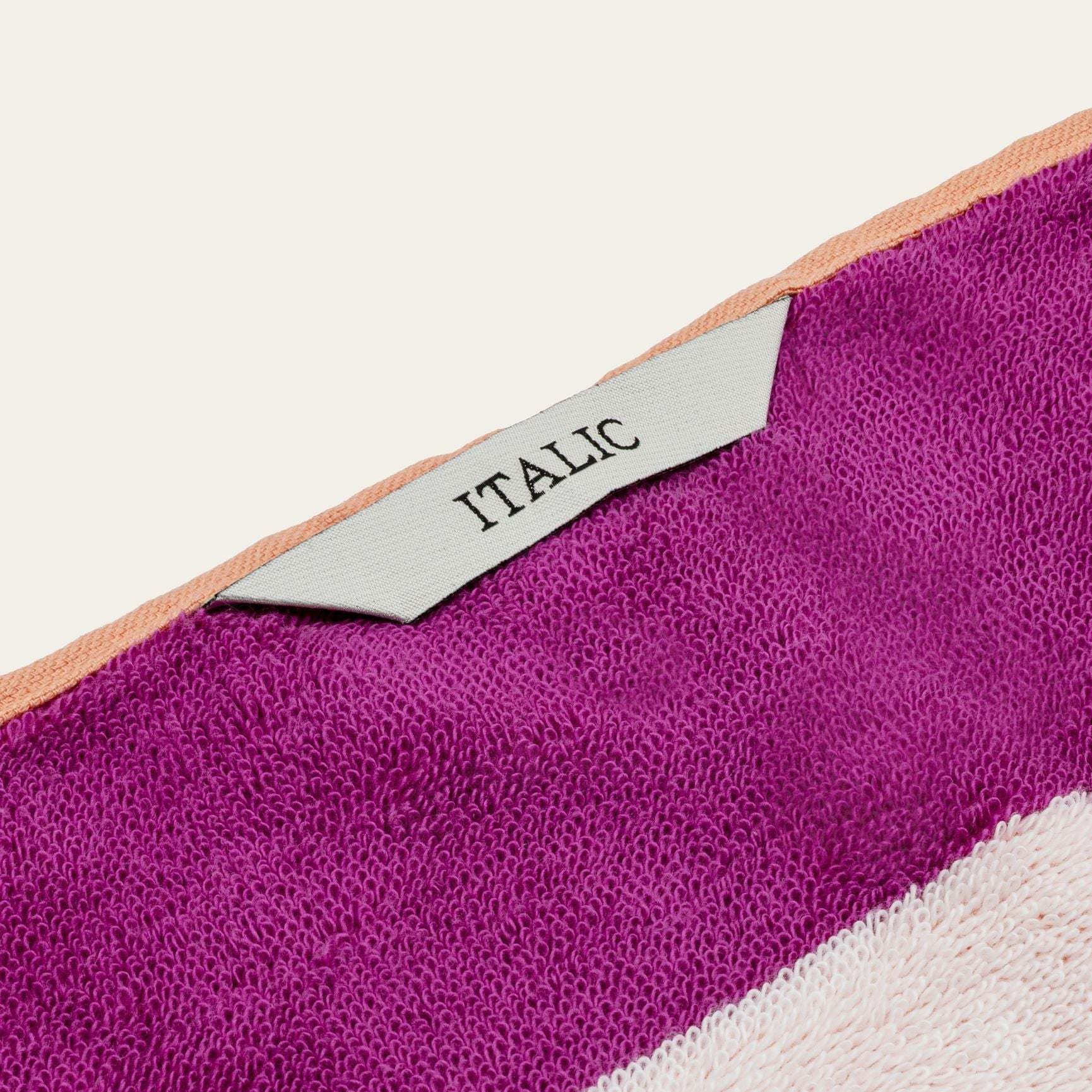 Bondi Australian Cotton beach towel in vivid magenta with a pale pink stripe, peach edging and woven ITALIC label