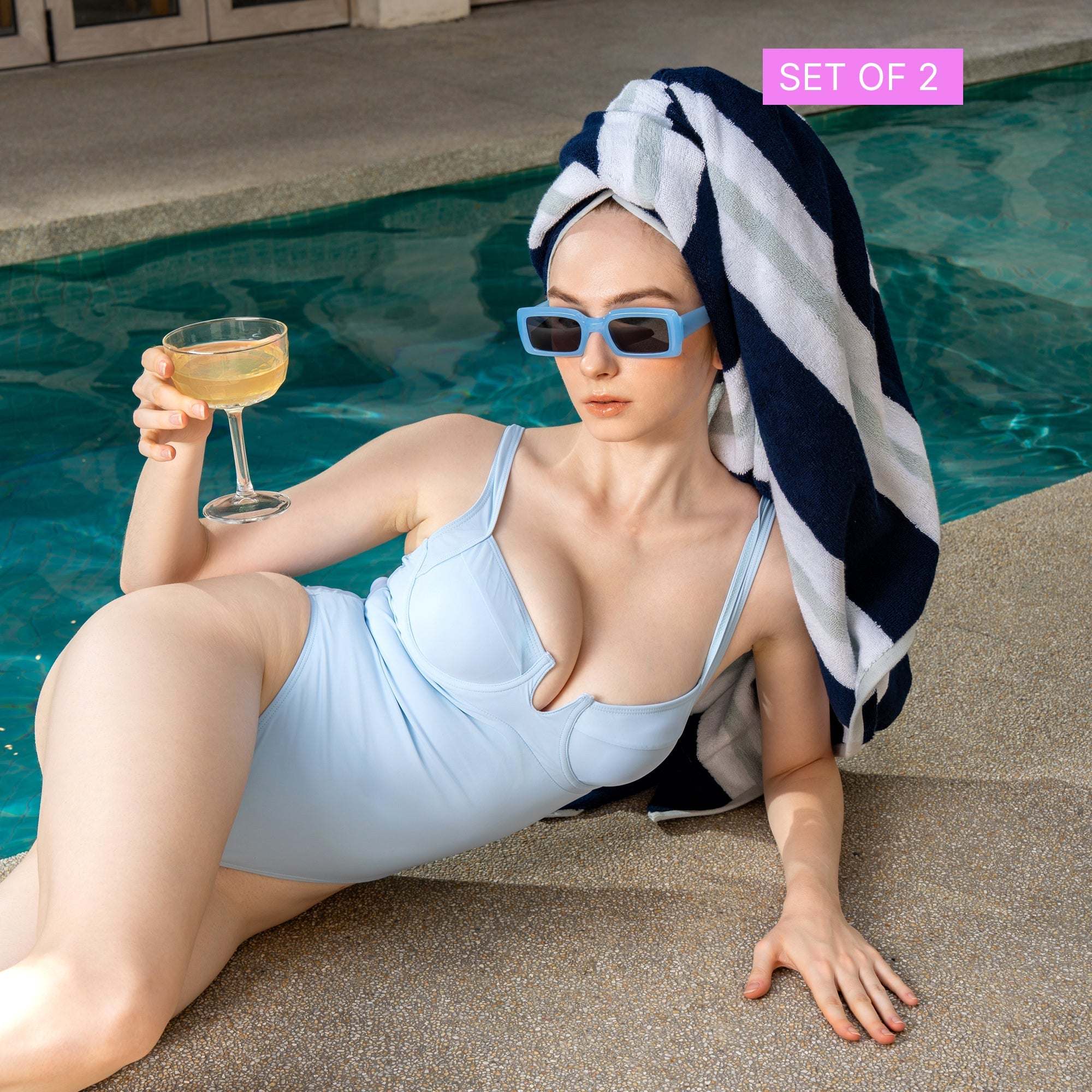 Bondi Australian Cotton beach towel in bold navy and white stripes draped over a woman's head by a pool
