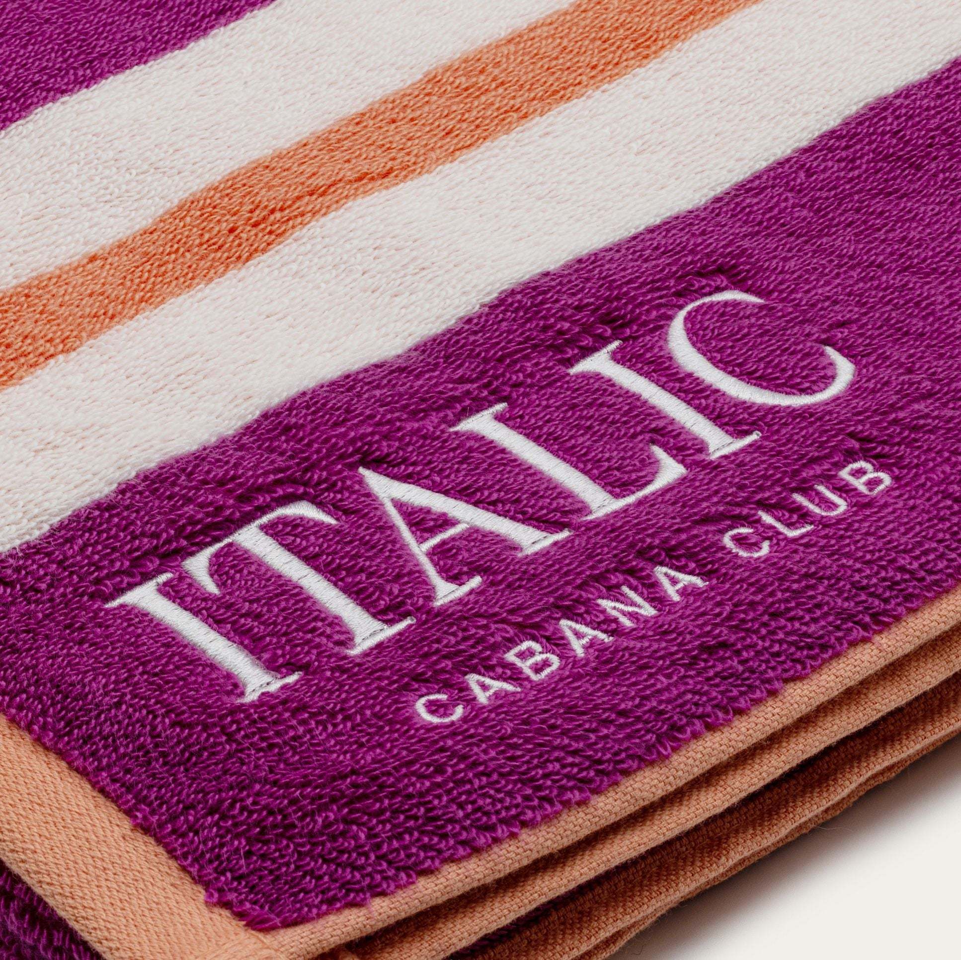 Bondi Australian Cotton beach towel in plum purple with white and orange stripes, plush terry texture and cabana club lettering