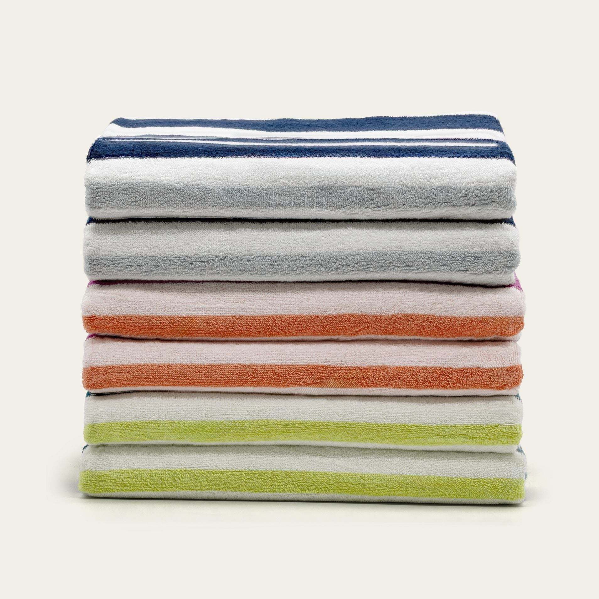 Bondi Australian Cotton beach towels stacked in soft white with navy, orange, and lime green stripe accents