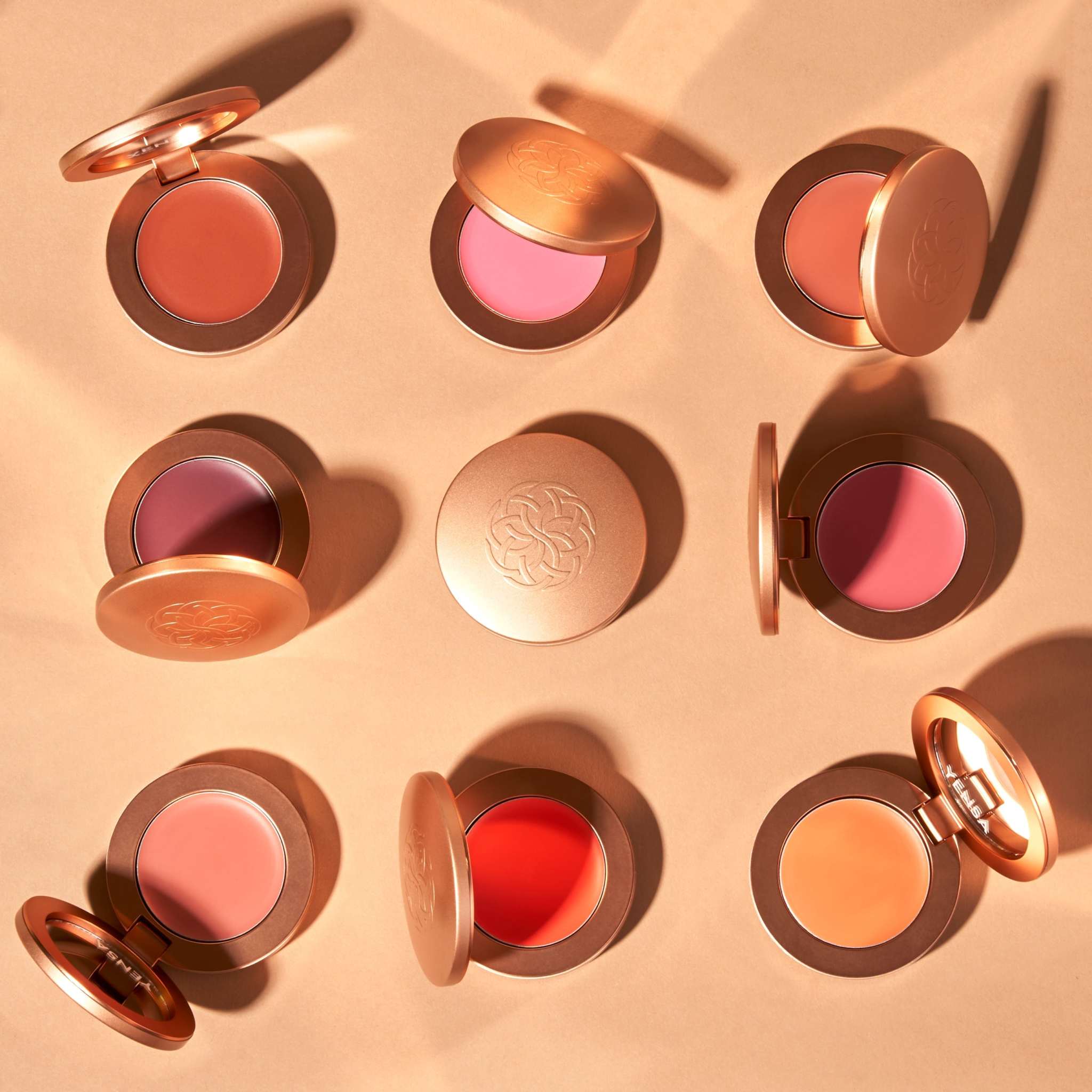 Buildable Cream Blush compacts in rose gold cases, showing silky cream pans in pink, coral, red and orange shades