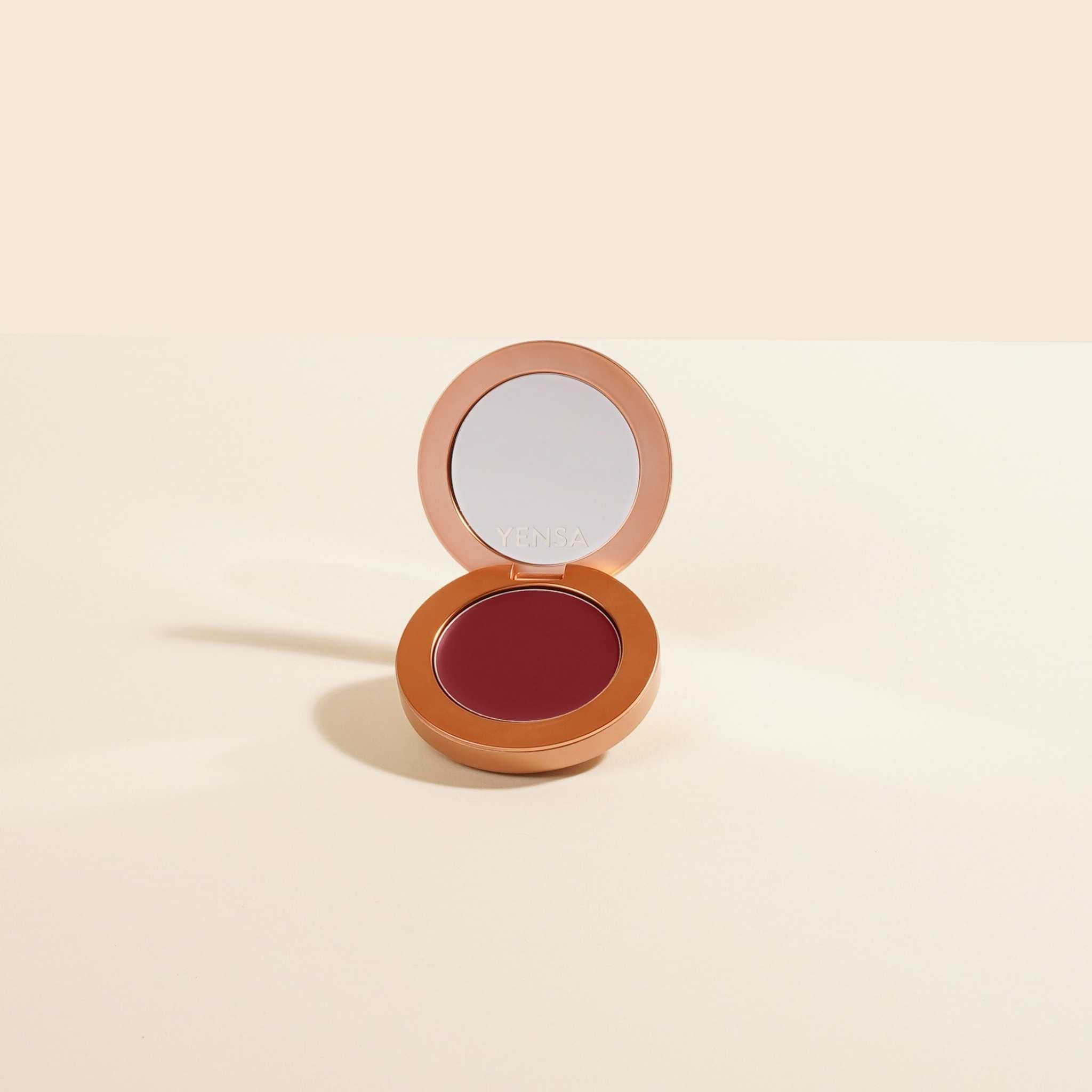 Buildable Cream Blush in a copper-toned compact with a deep berry cream pan and mirrored lid