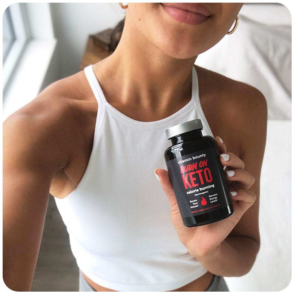 Burn On Keto supplement in a black bottle with red and white label, held by a person wearing a white top