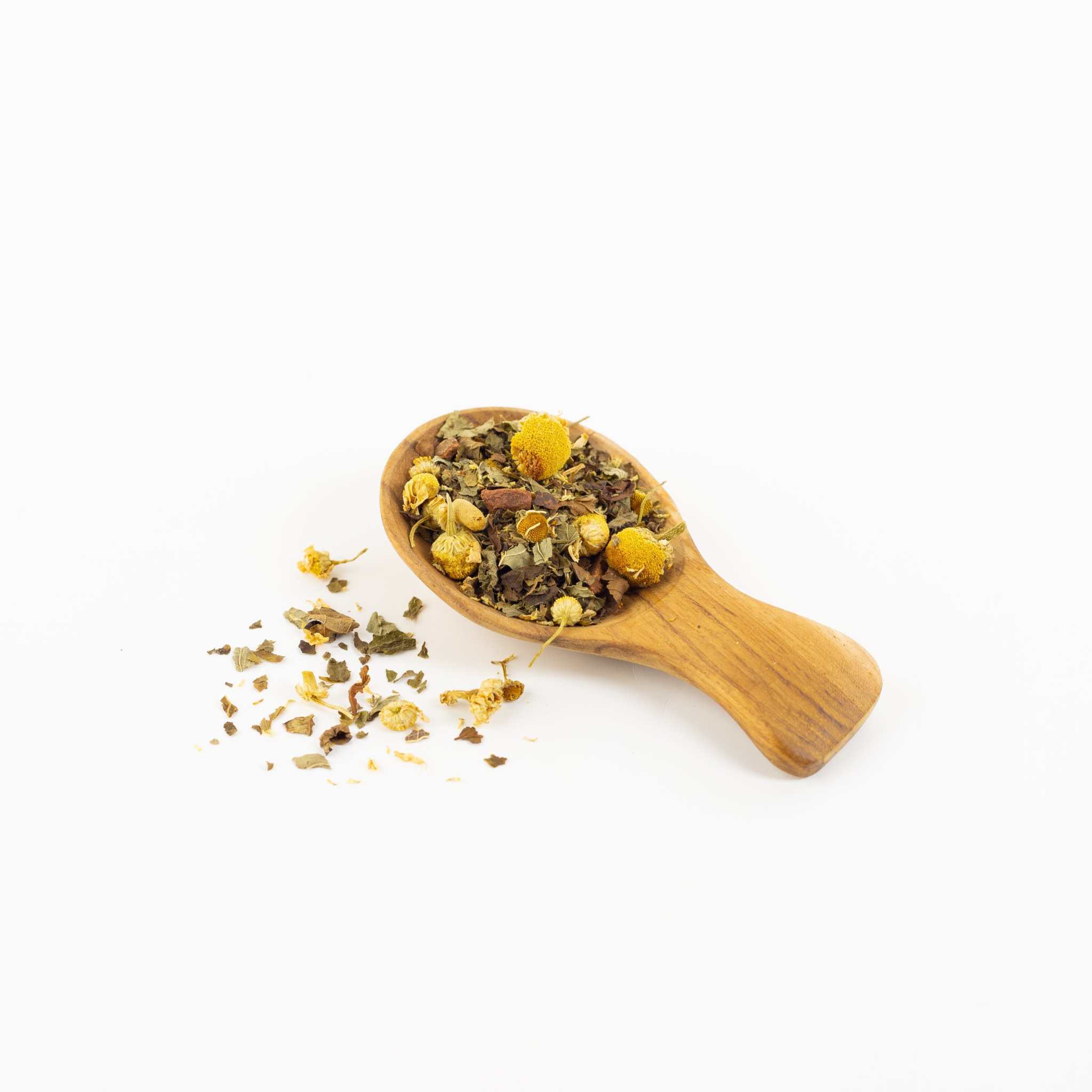 Calm-In-A-Teacup loose leaf organic chamomile tea blend with yellow chamomile flowers, cinnamon, and dried herbs on a wooden scoop