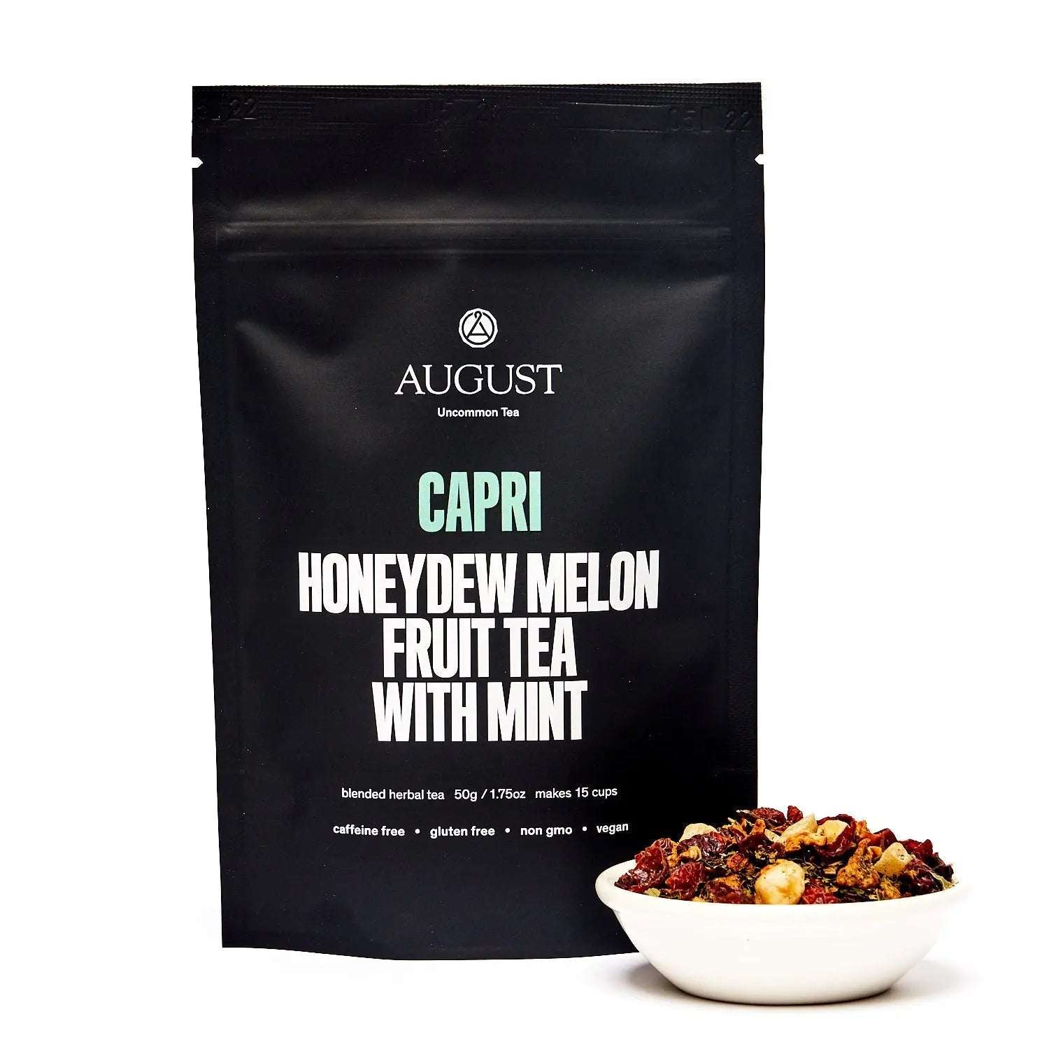 Capri - Honeydew Melon Mint Tea in a black August resealable pouch beside a bowl of colorful dried fruit tea blend