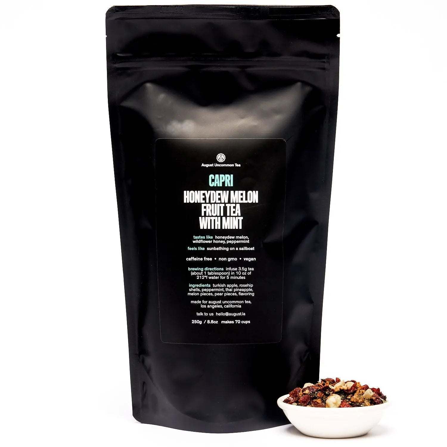 Capri - Honeydew Melon Mint Tea in a black resealable pouch with a bowl of colorful dried fruit tea blend